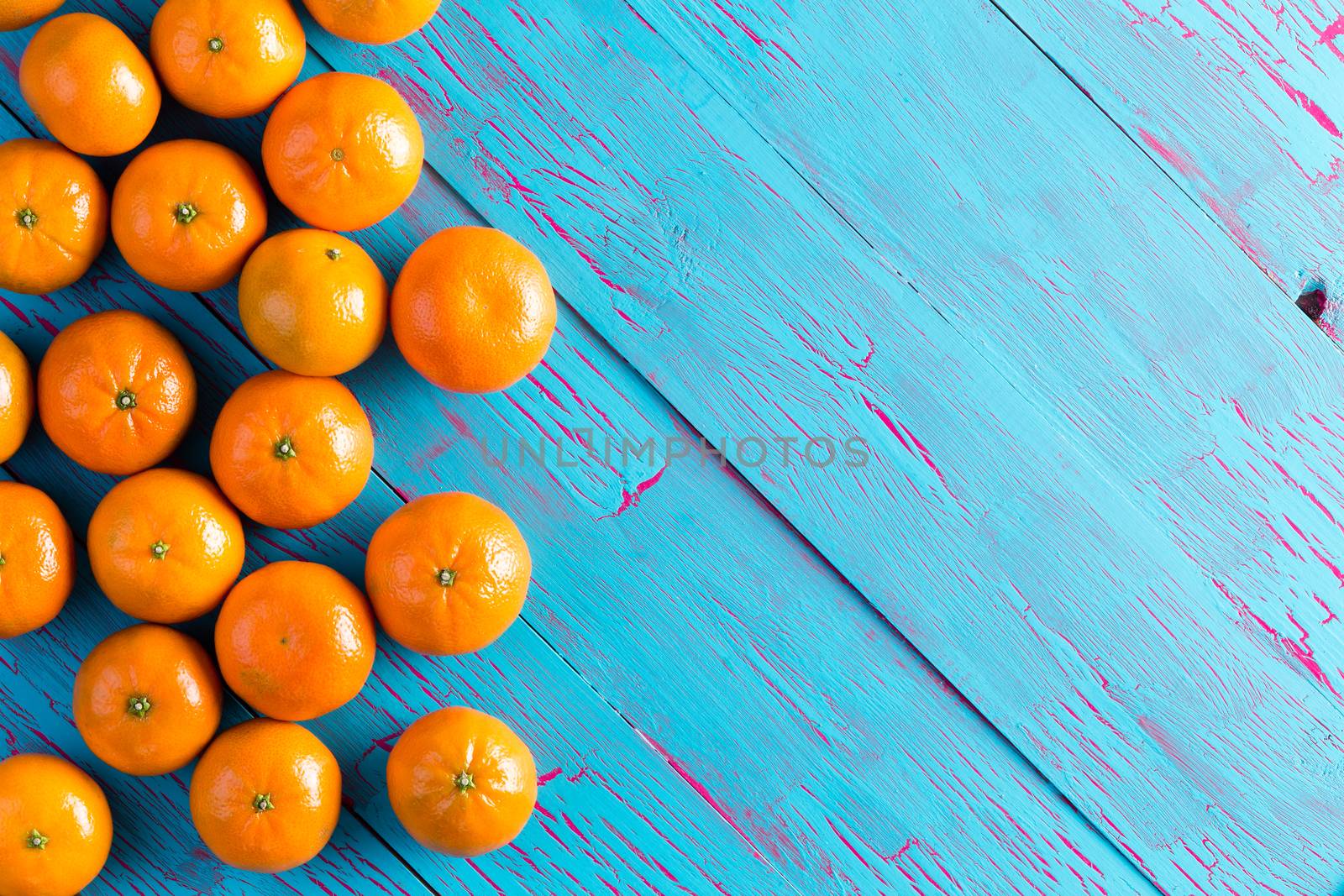 Colorful fresh orange mandarins laid out on a rustic cracked blue painted wooden picnic table viewed from above with copy space