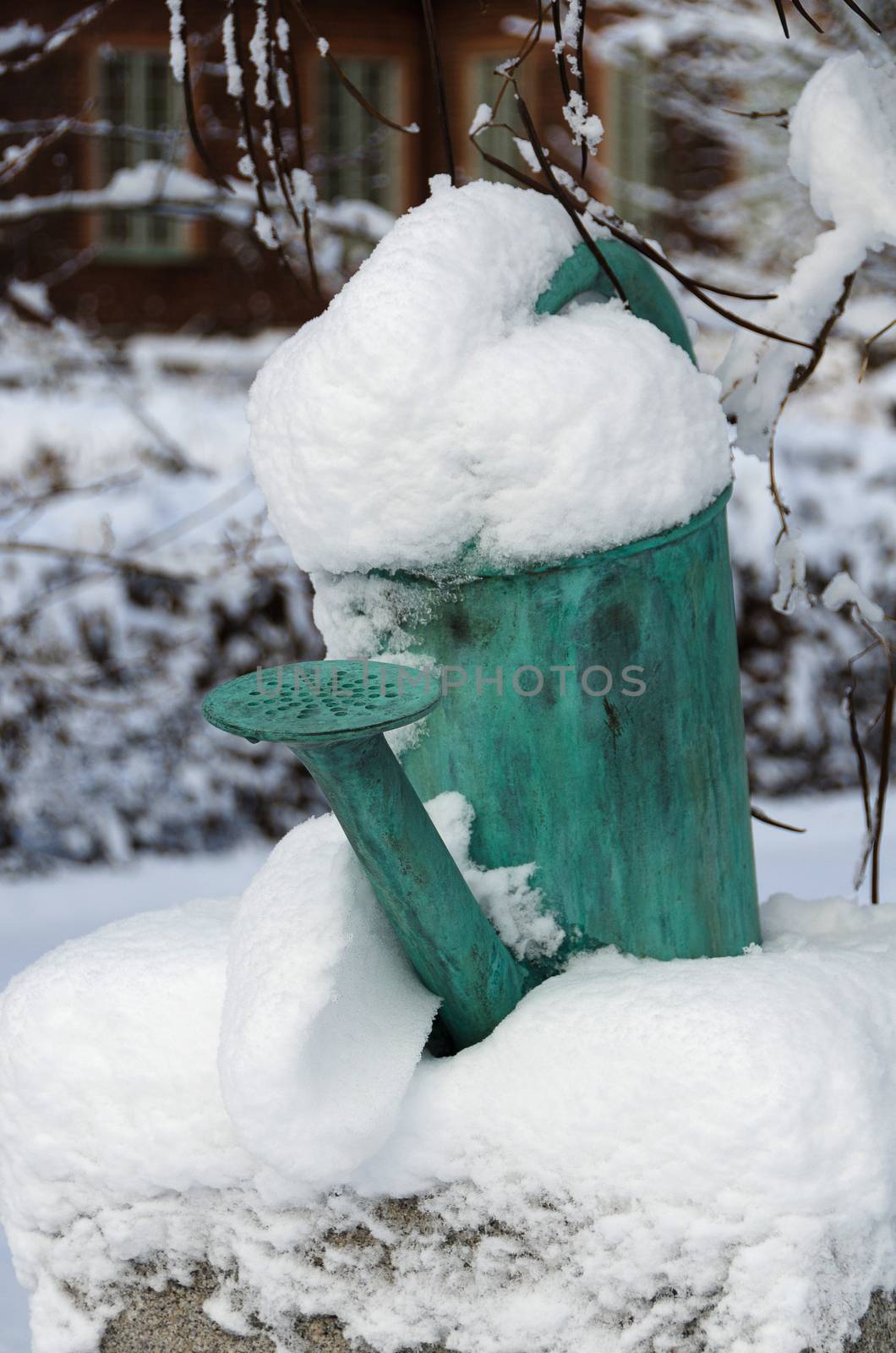 one old watering can on a stone with snow on