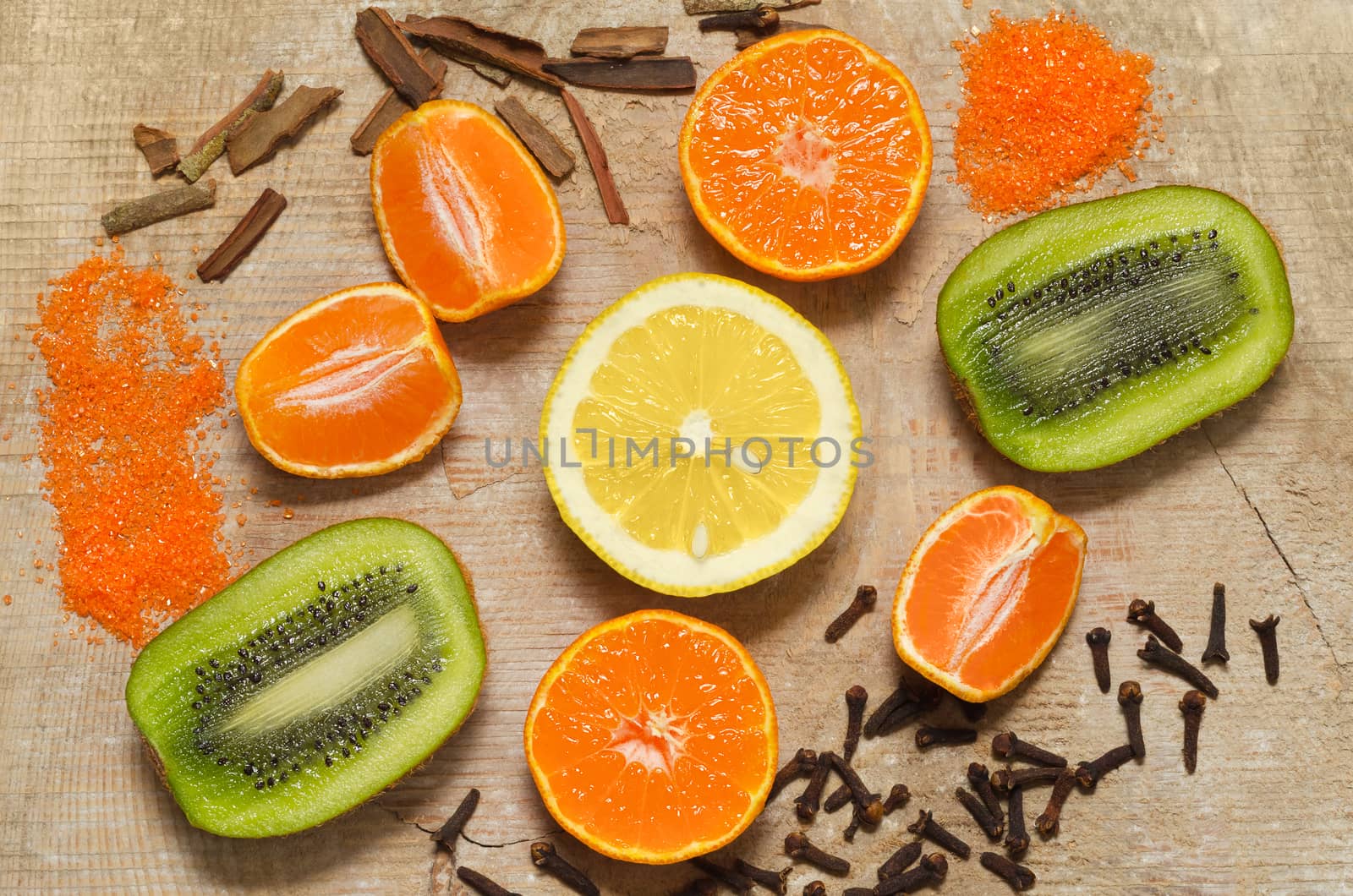 Half a lemon, kiwi, tangerines and spices, lying on a texture surface of an old tree.