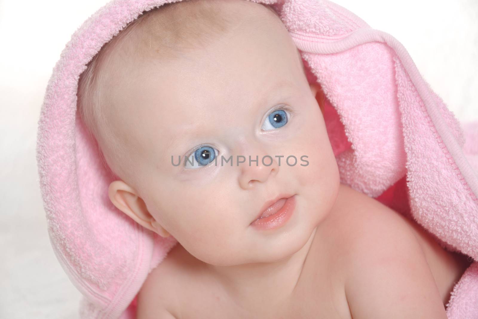 Adorable baby girl under a pink towel by jordano
