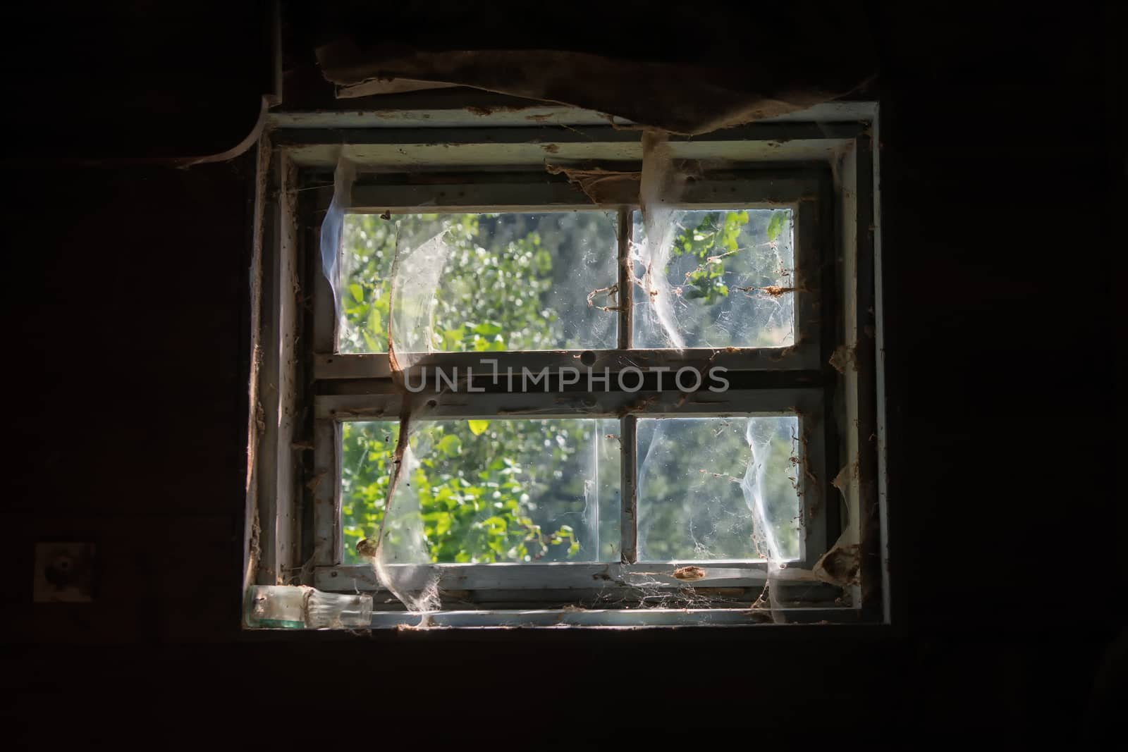 Old window on the soil of the old house with the net