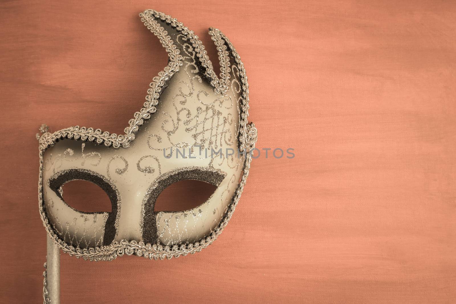 Colorful carnival mask on a brown textured background. Masks with theater concept. Top view with copy space