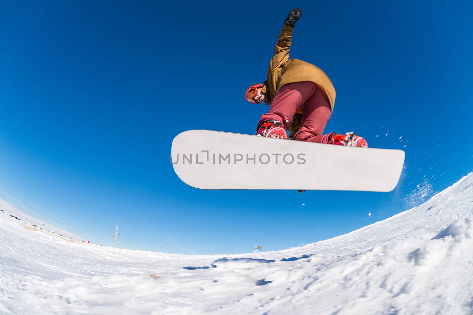 Snowboarder executing a radical jump against blue sky.