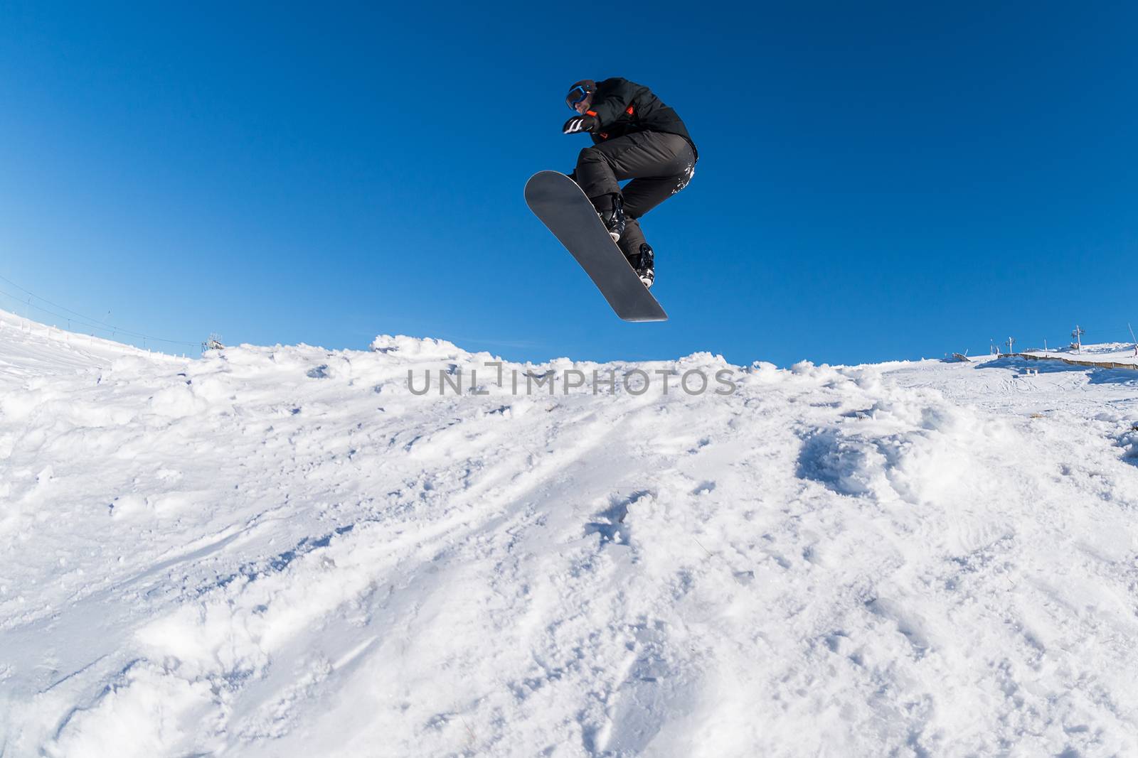 Snowboarder executing a radical jump against blue sky.