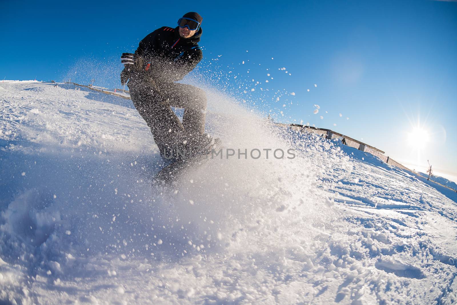 Snowboard freerider in the mountains against sun shine in blue sky.