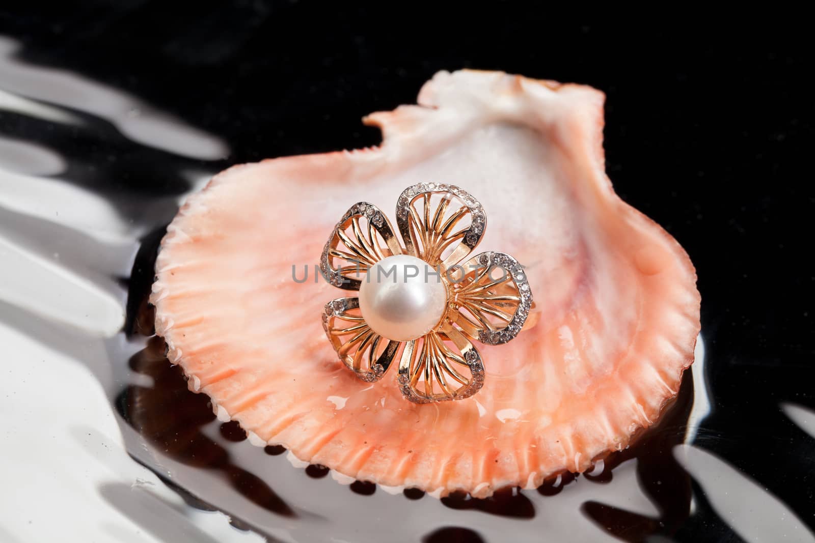 Golden ring with the pearl and the sea shell in the water