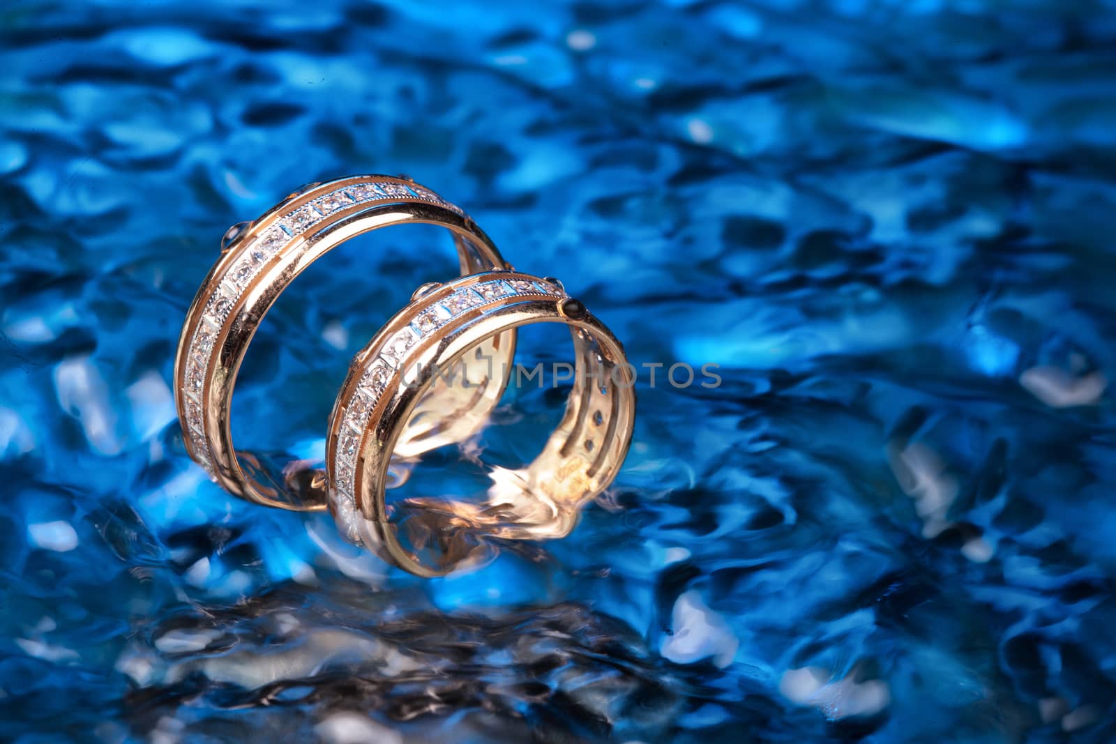 Two engagement golden rings in the ater with air bubbles