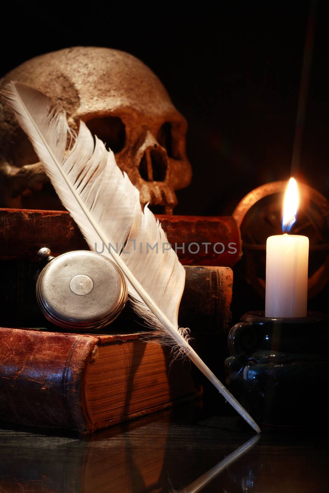 Medieval science. Vintage still life with old books and quill near lighting candle