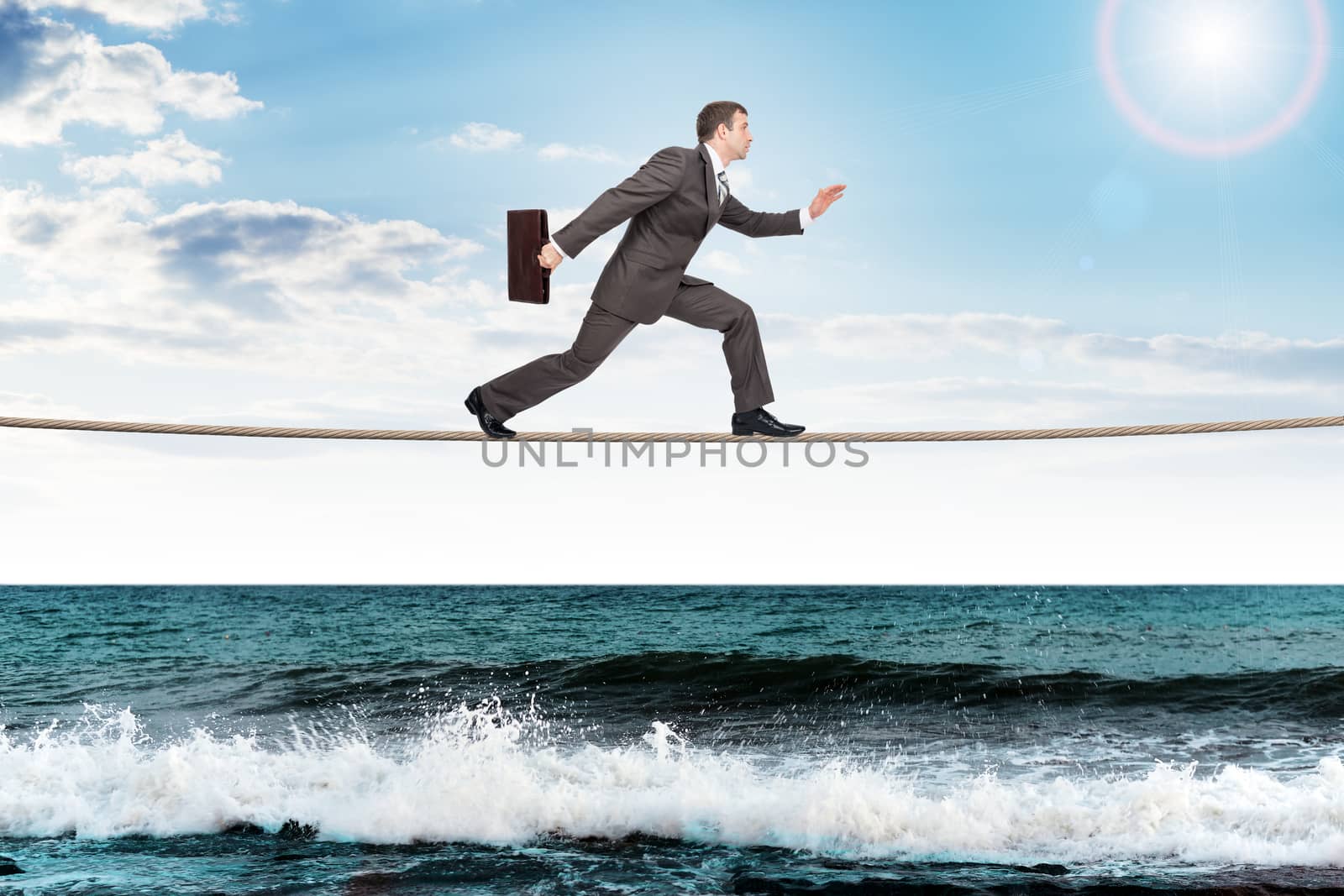 Businessman with suitcase running on rope, danger concept
