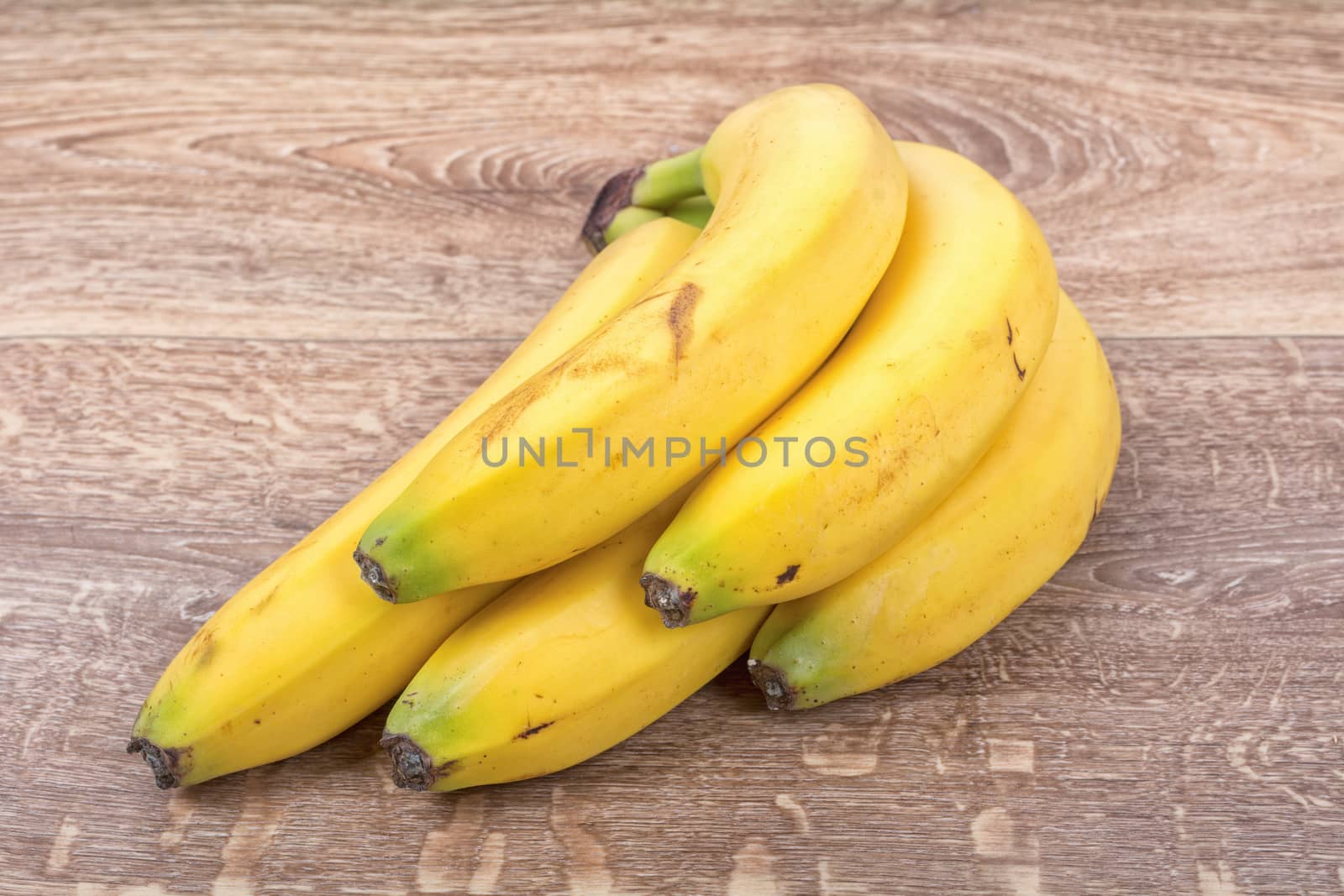 A clump of yellow bananas on a brown wooden background