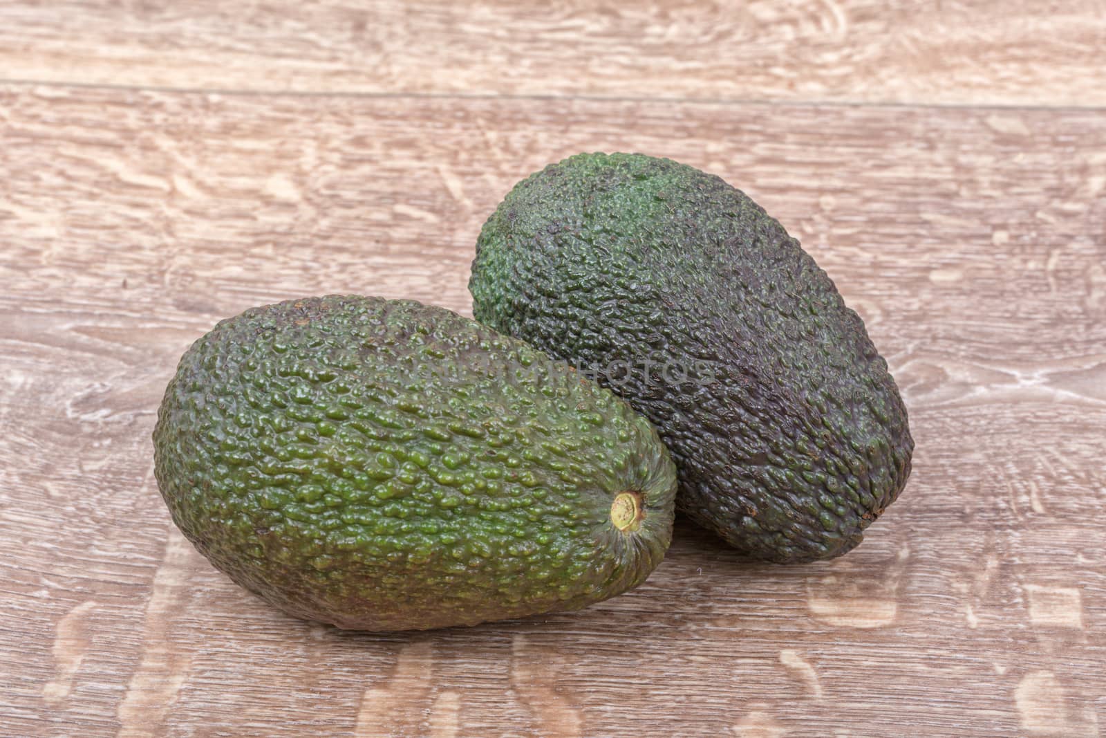 Two of avocado on a brown wooden background