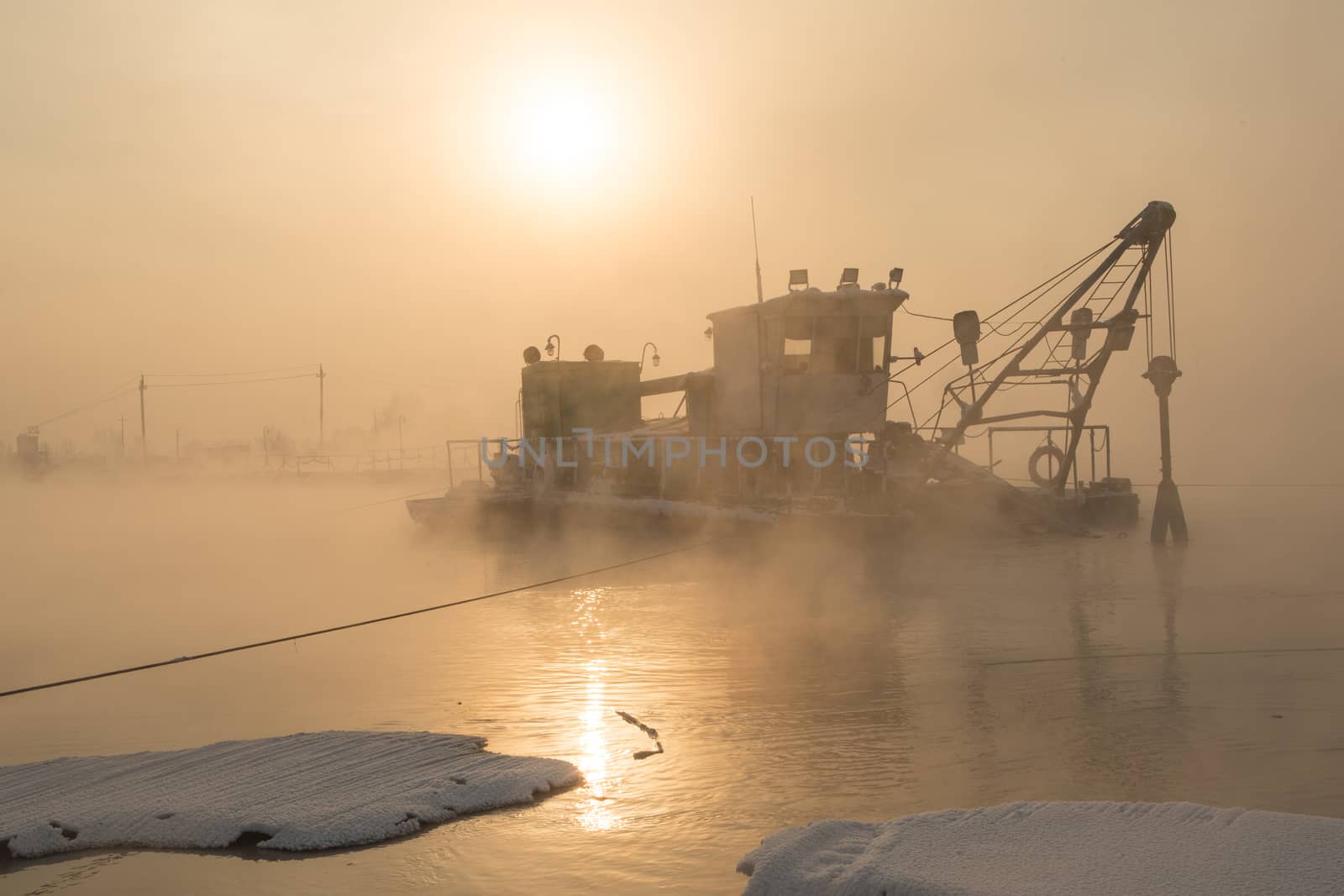 a dredger boat in winter mist at sunset