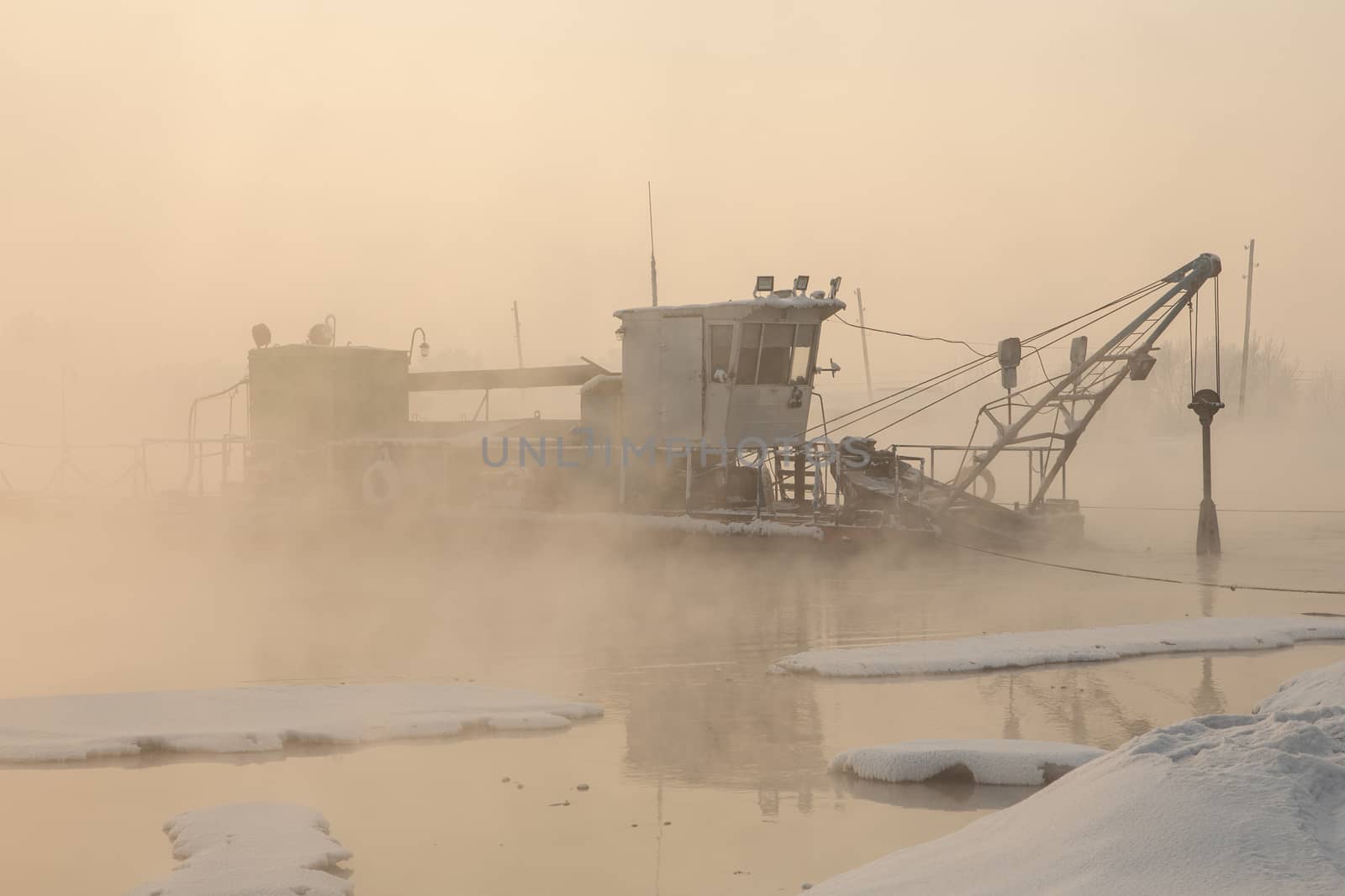 a dredger boat in winter mist at sunset