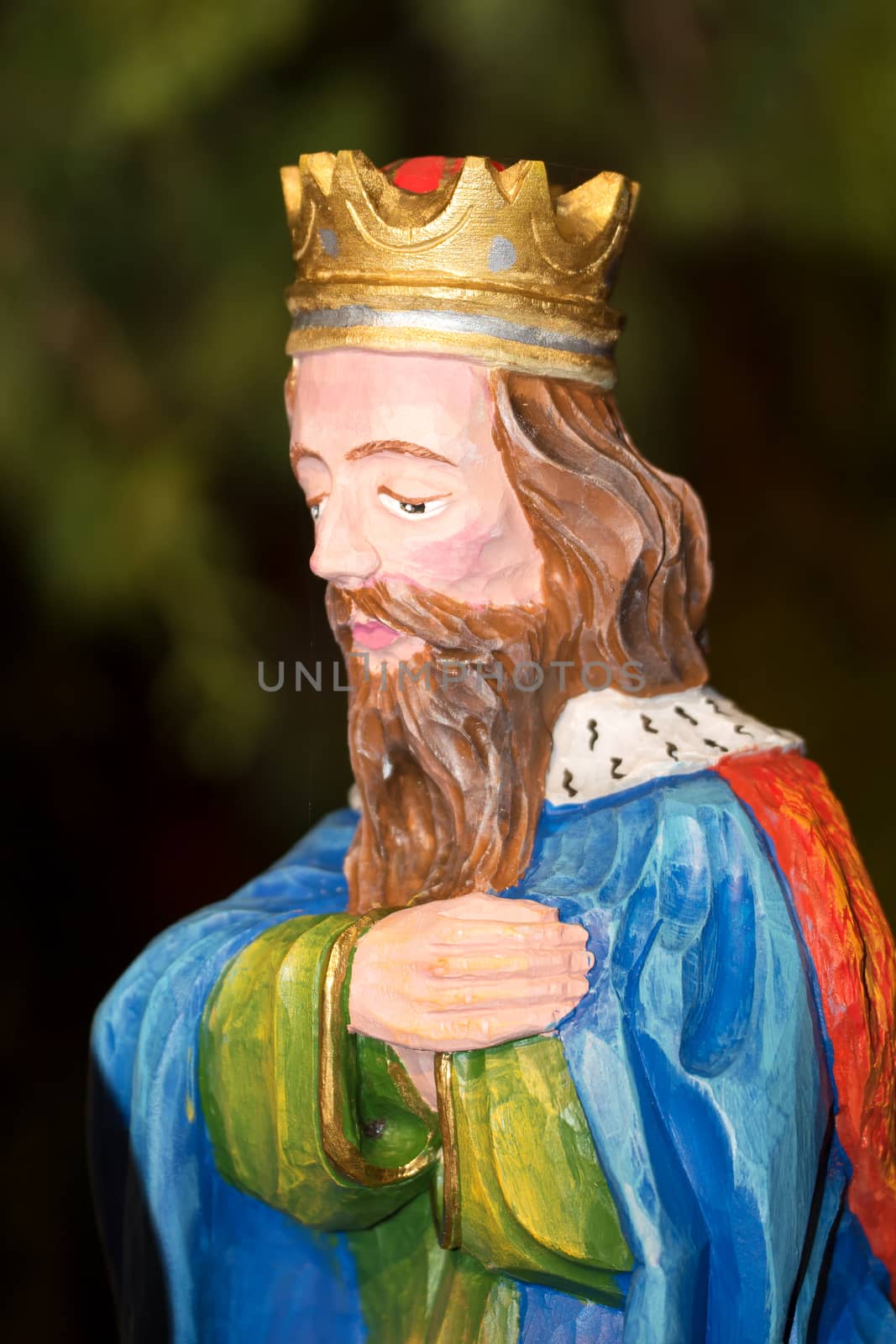 Colored wood sculpture of King with blurred background.