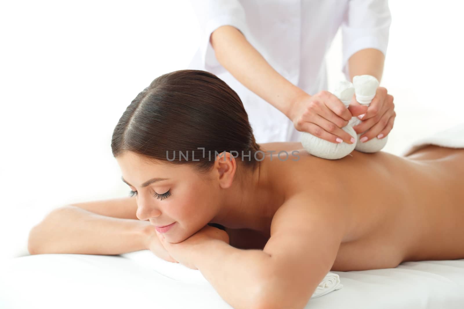 Woman in spa getting massage with herbal balls