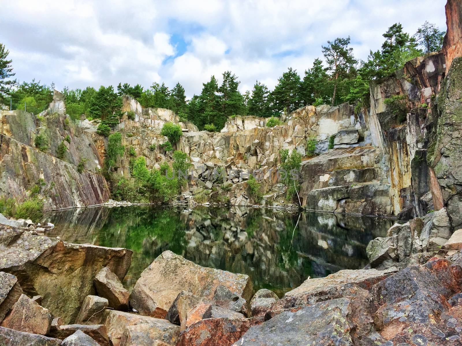 Beautiful lake in Sweden, surrounded by rocks and trees. Ancient stone quarry, abandoned many years ago.