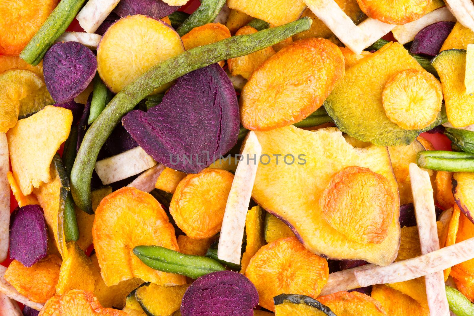 Background food texture of organic healthy veggie chips made form an assortment of colorful dried sliced vegetables in a full frame view