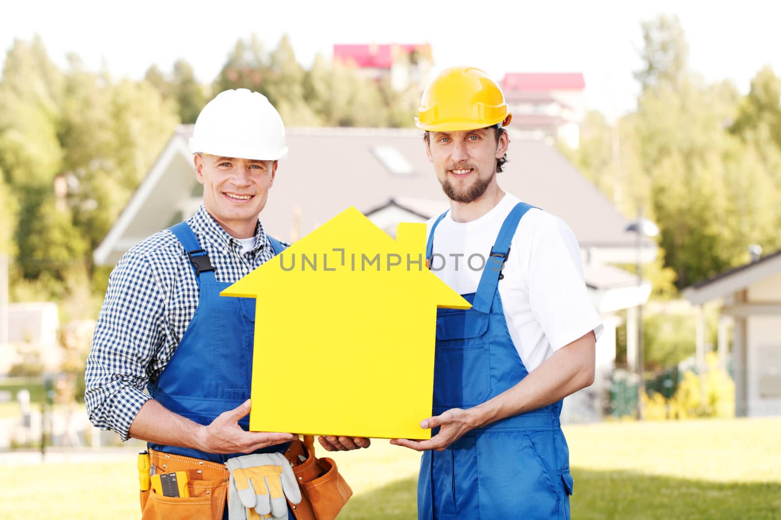 Happy smiling workers in hardhats holding house model