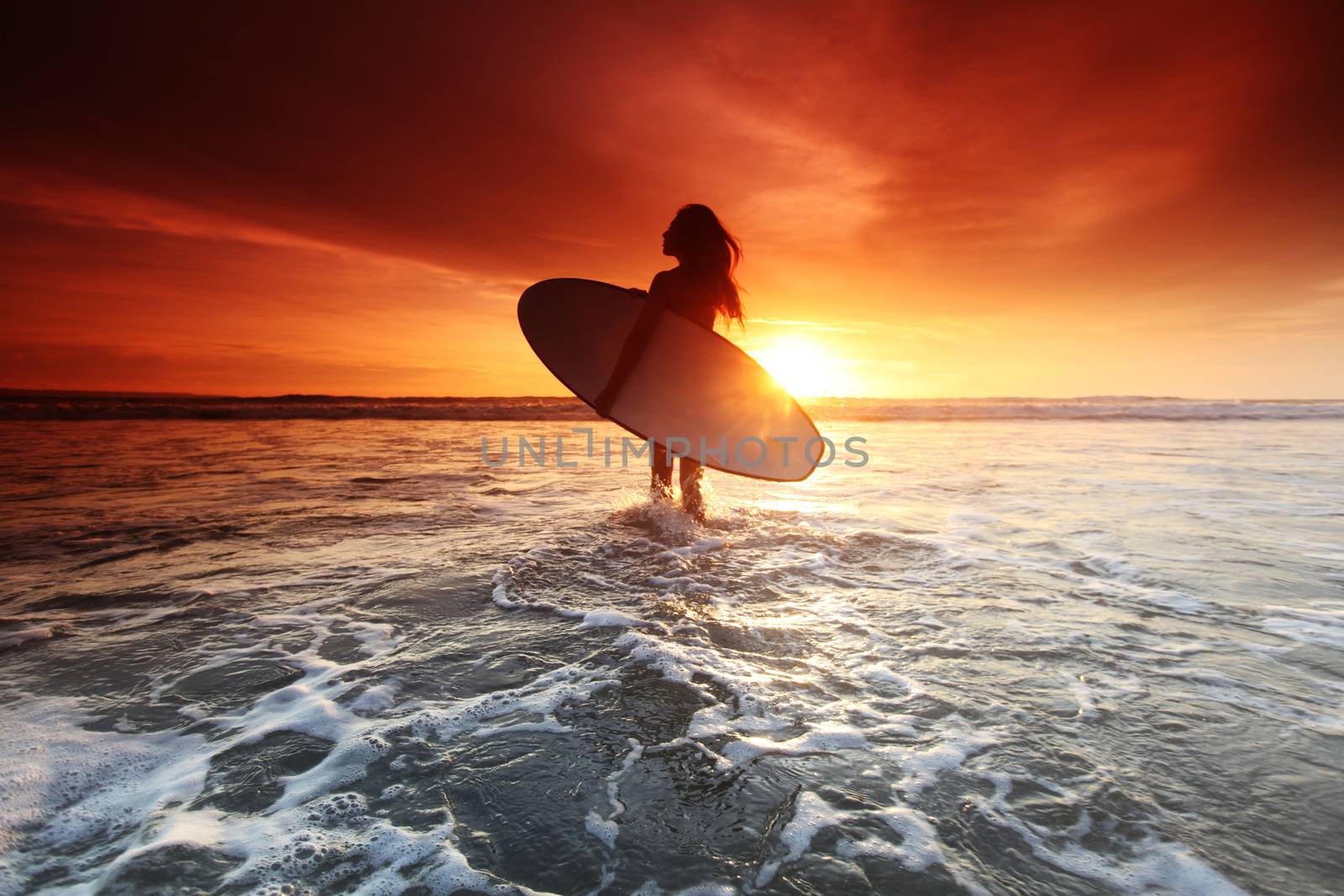 Beautiful surfer woman on the beach at sunset