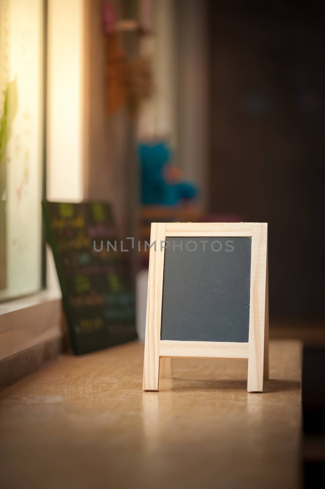 Small A-frame black board with blank area for text or message on wood bar in cafe wih low key scene