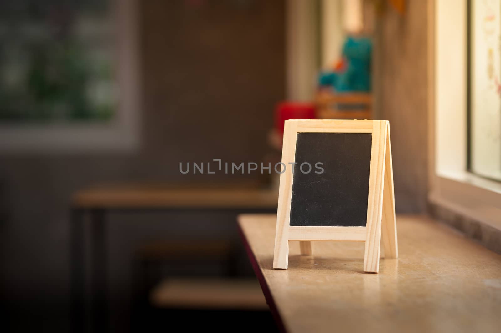 Small A-frame black board with blank area for text or message on wood bar in cafe at morning time