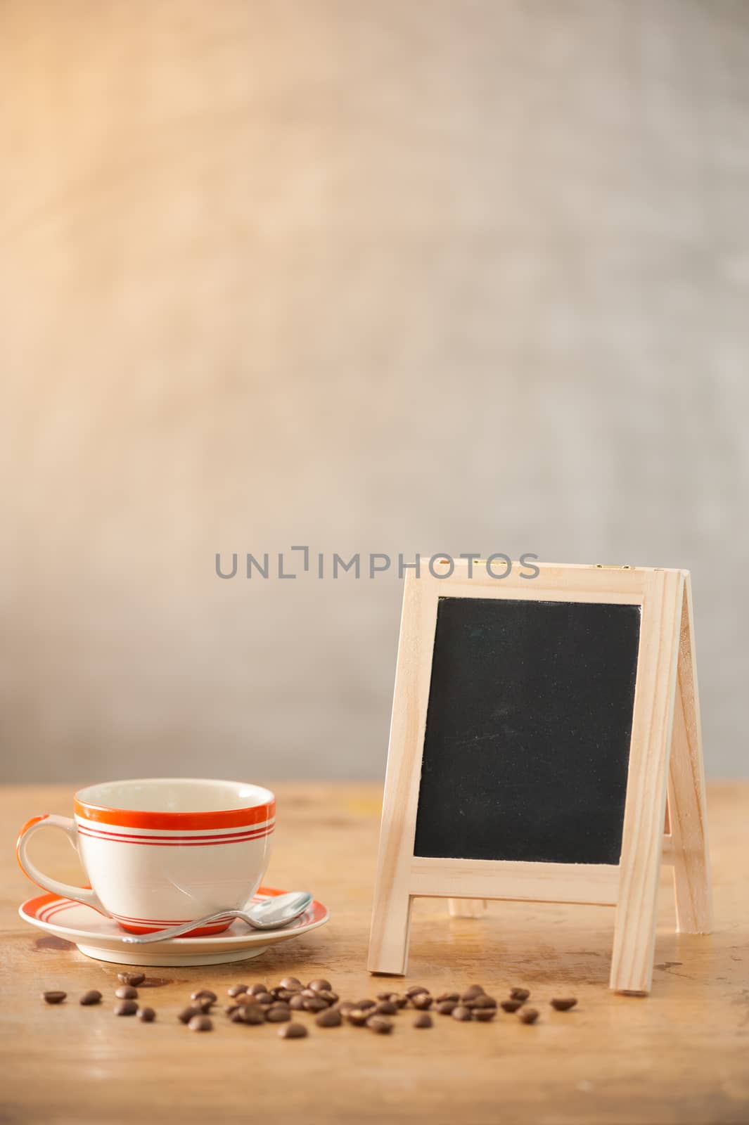 Small A-frame black board with blank area for text or message and coffee cup on wood table in morning time