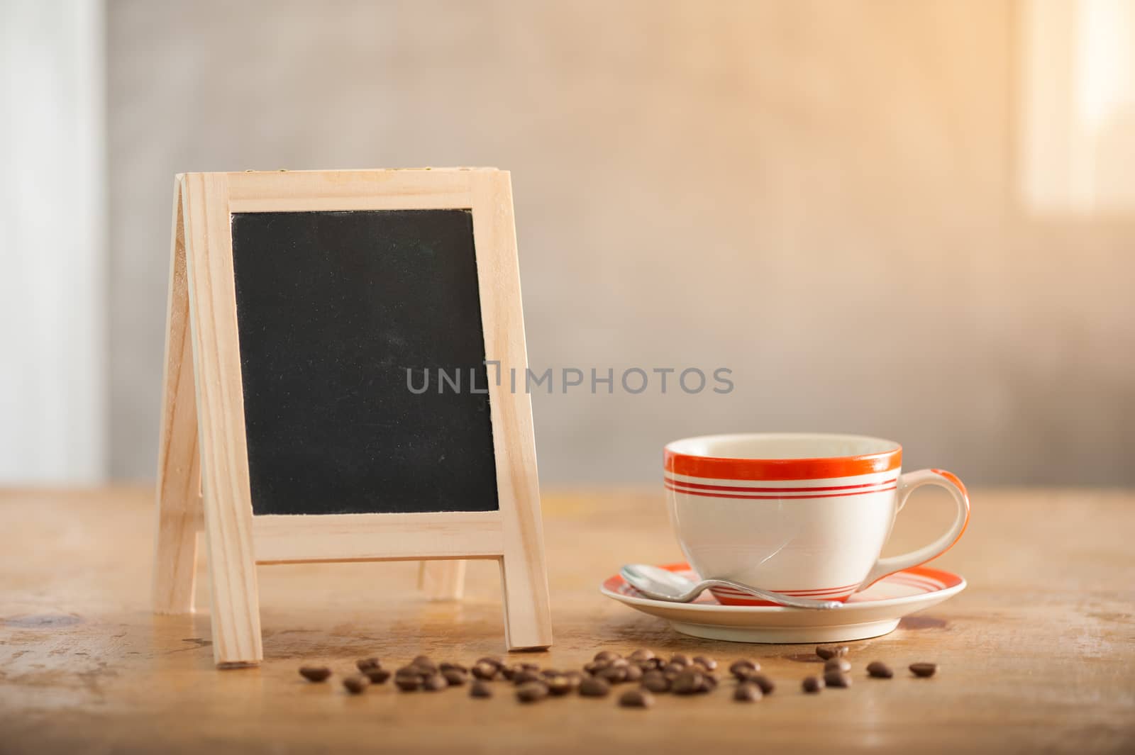 Small A-frame black board with blank area for text or message and coffee cup on wood table in morning time