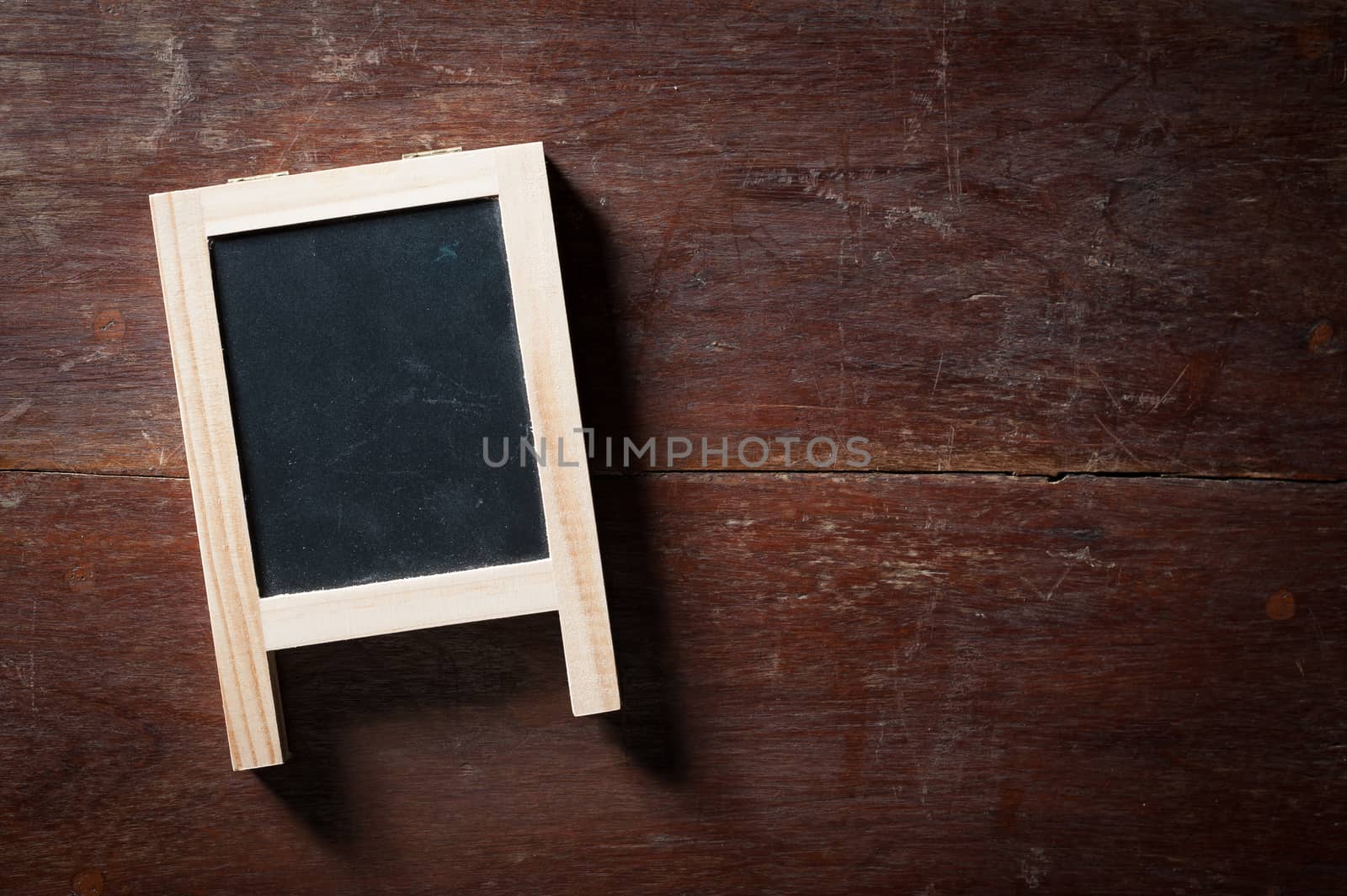 Small A-frame black board with blank area for text or message on rustic wood table with low key scene.