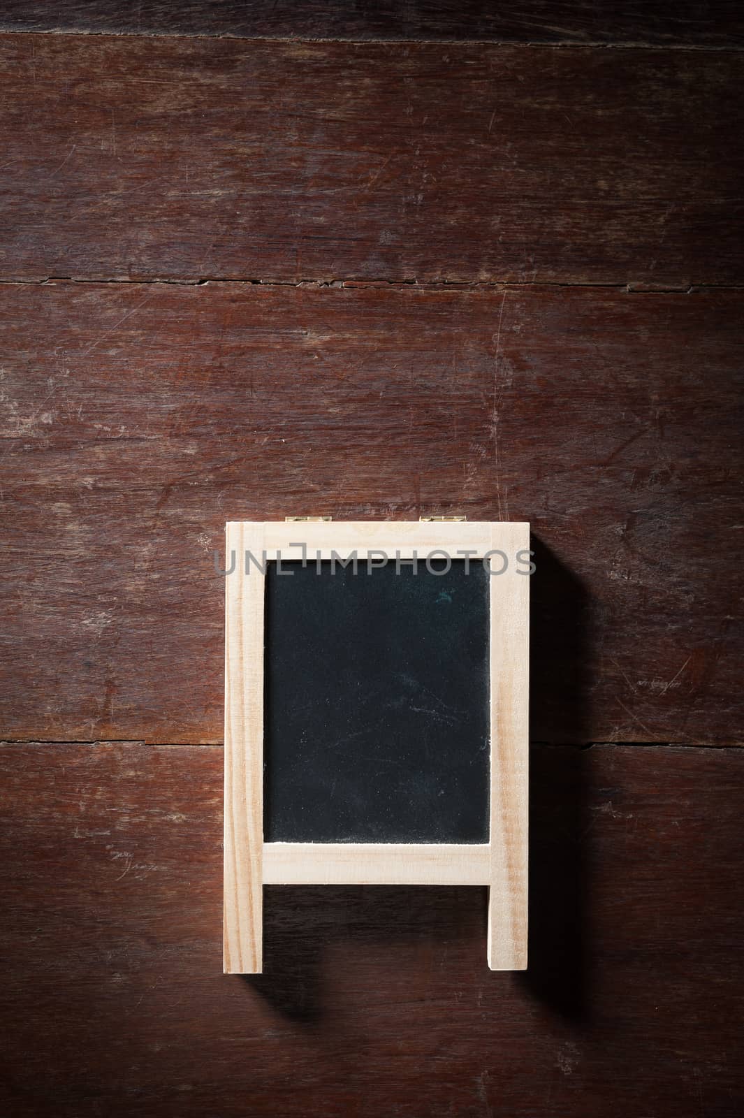 Small A-frame black board with blank area for text or message on rustic wood table with low key scene.
