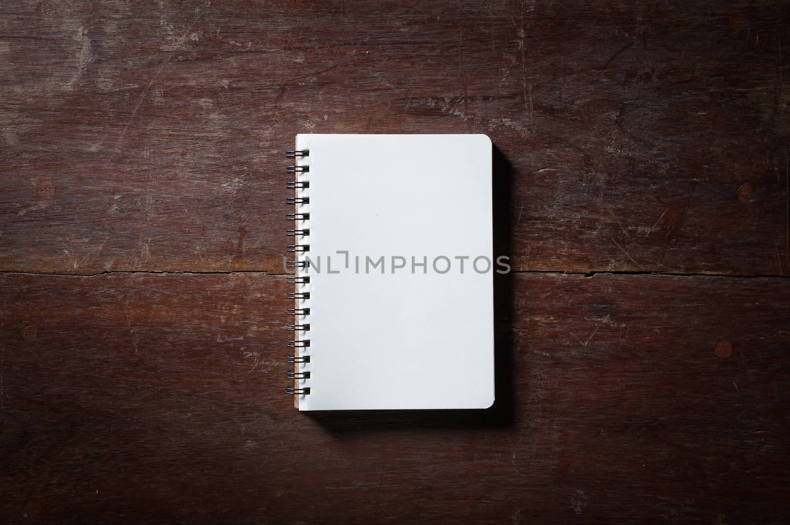 Small opened notepad with blank area for text or message and pen on rustic wood table with low key scene and vinatage filter effect