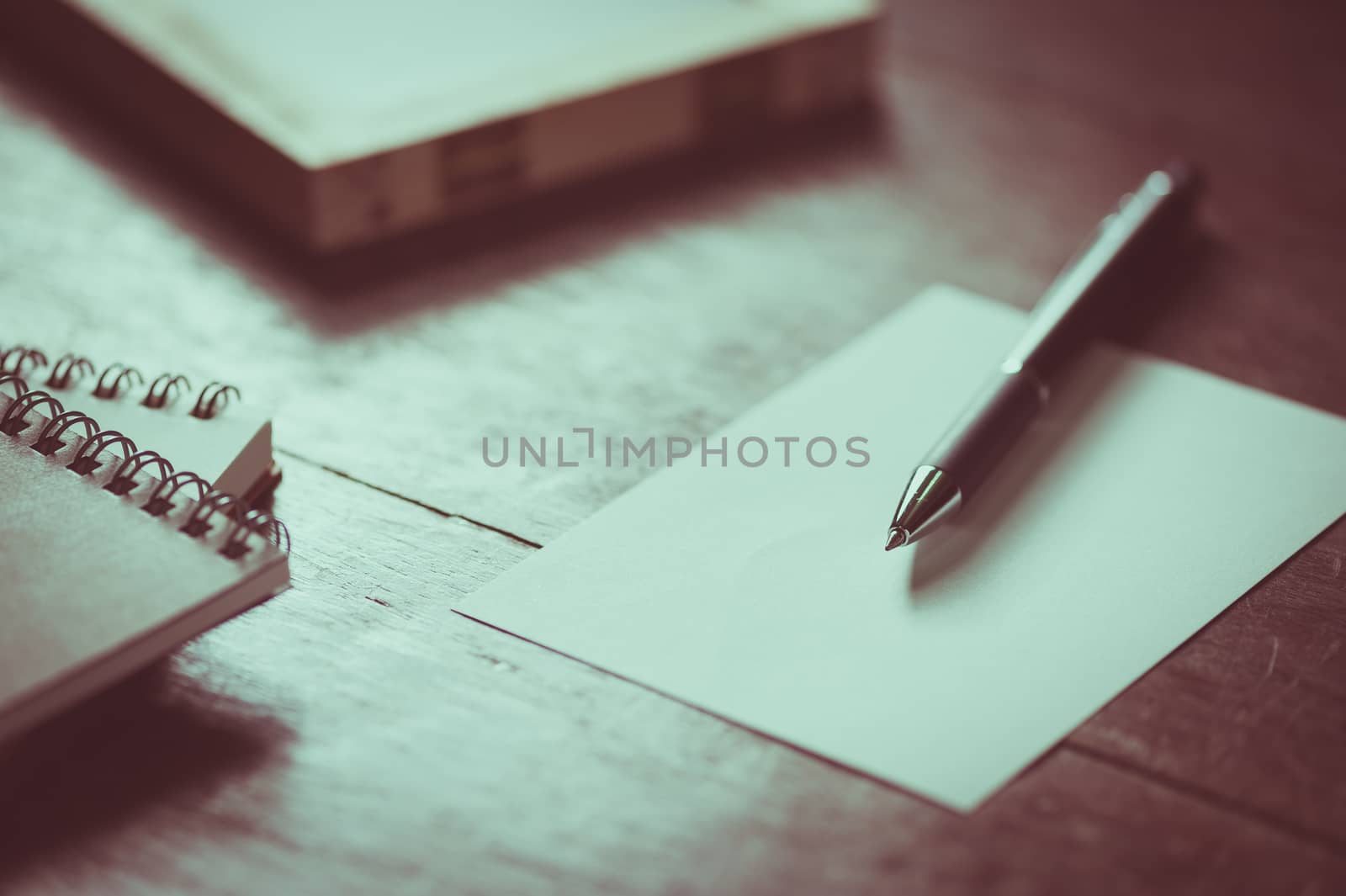 Blank paper on wood table with notebooks on wood table with vintage filter effect