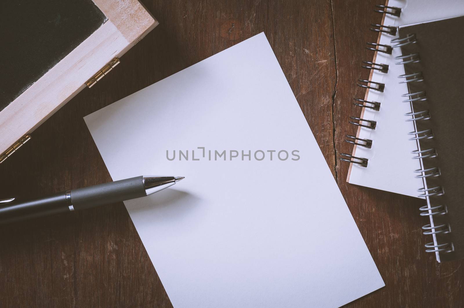 Blank paper on wood table with notebooks on wood table with vintage filter effect