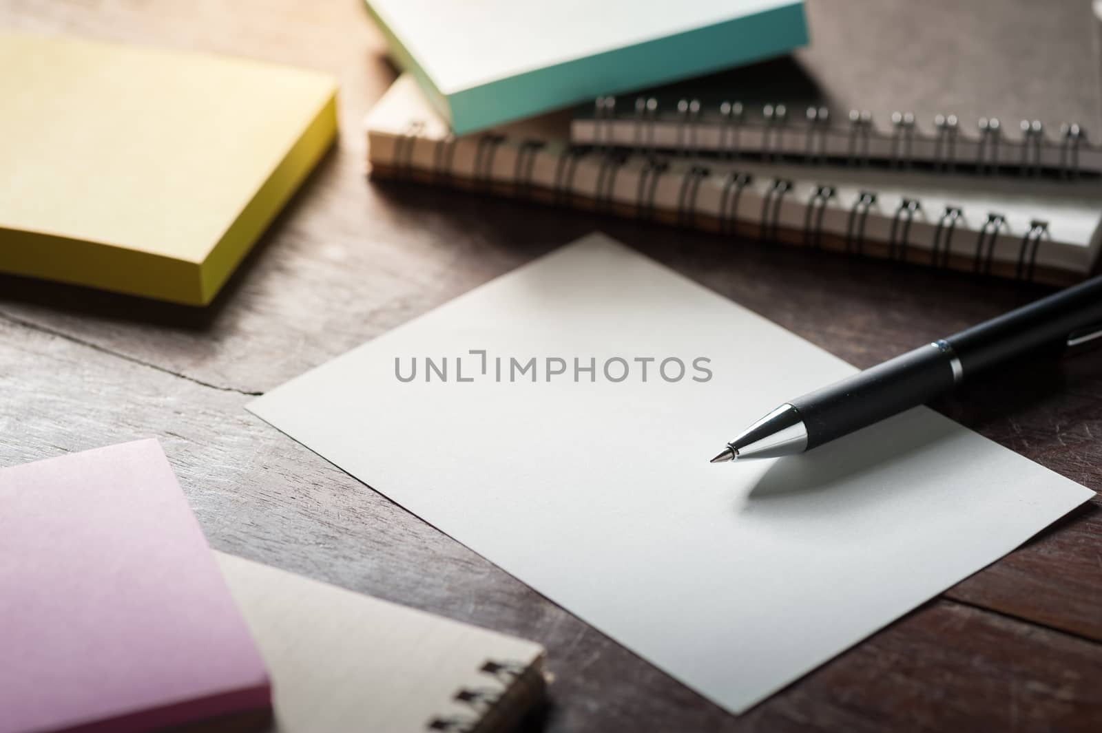 Blank paper on wood table with notebooks on wood table with low key scene
