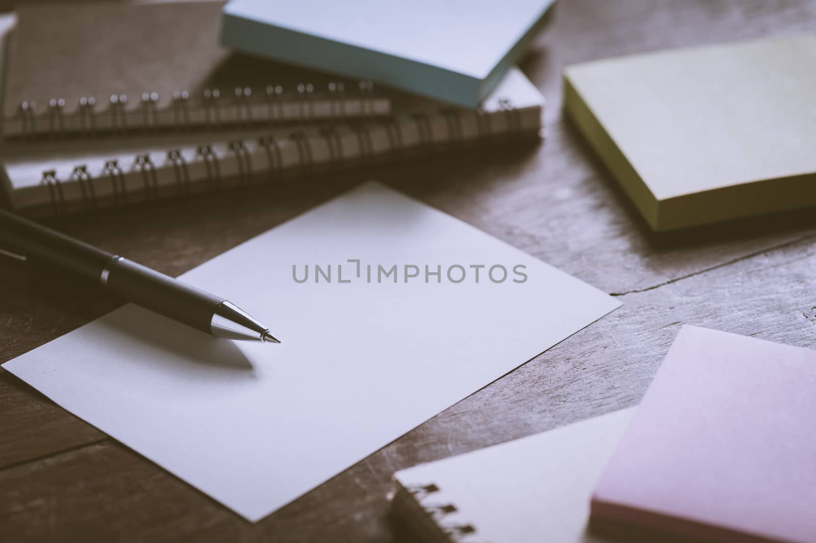 Blank paper on wood table with notebooks on wood table with low key scene and vintage filter effect