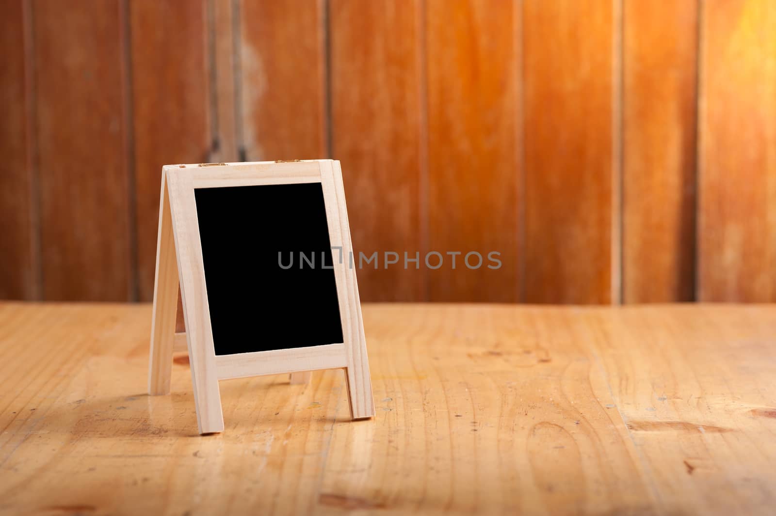 Small A-frame black board with blank area for text or message on wood table