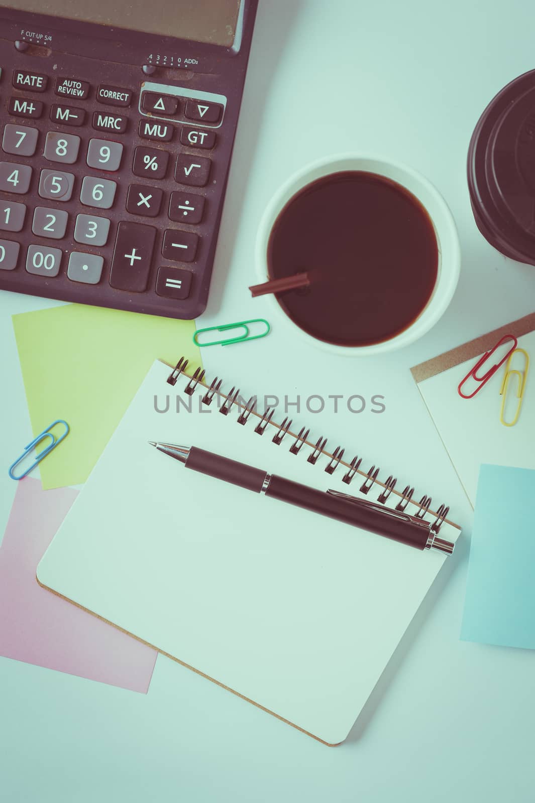 Opened notebook, pen, sticky paper, and take away coffee cup on office table with vintage filter effect