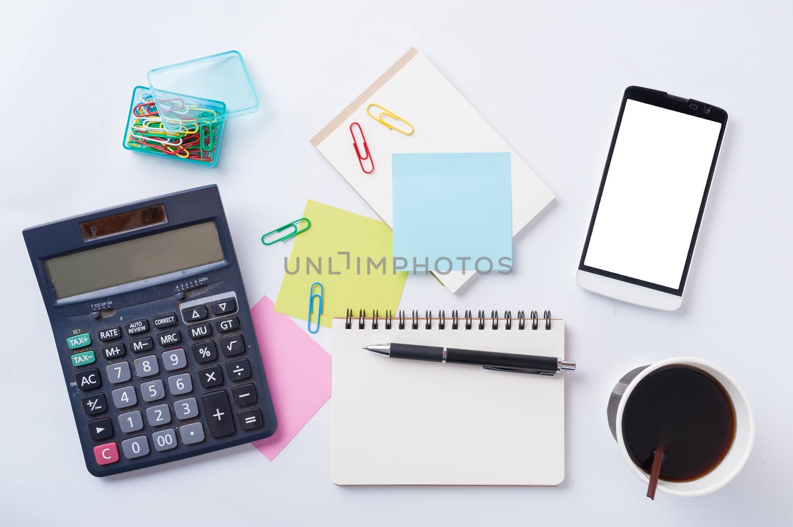 Opened notebook with blank space for text or message, sticky paper, calculator, and take away coffee cup on office table