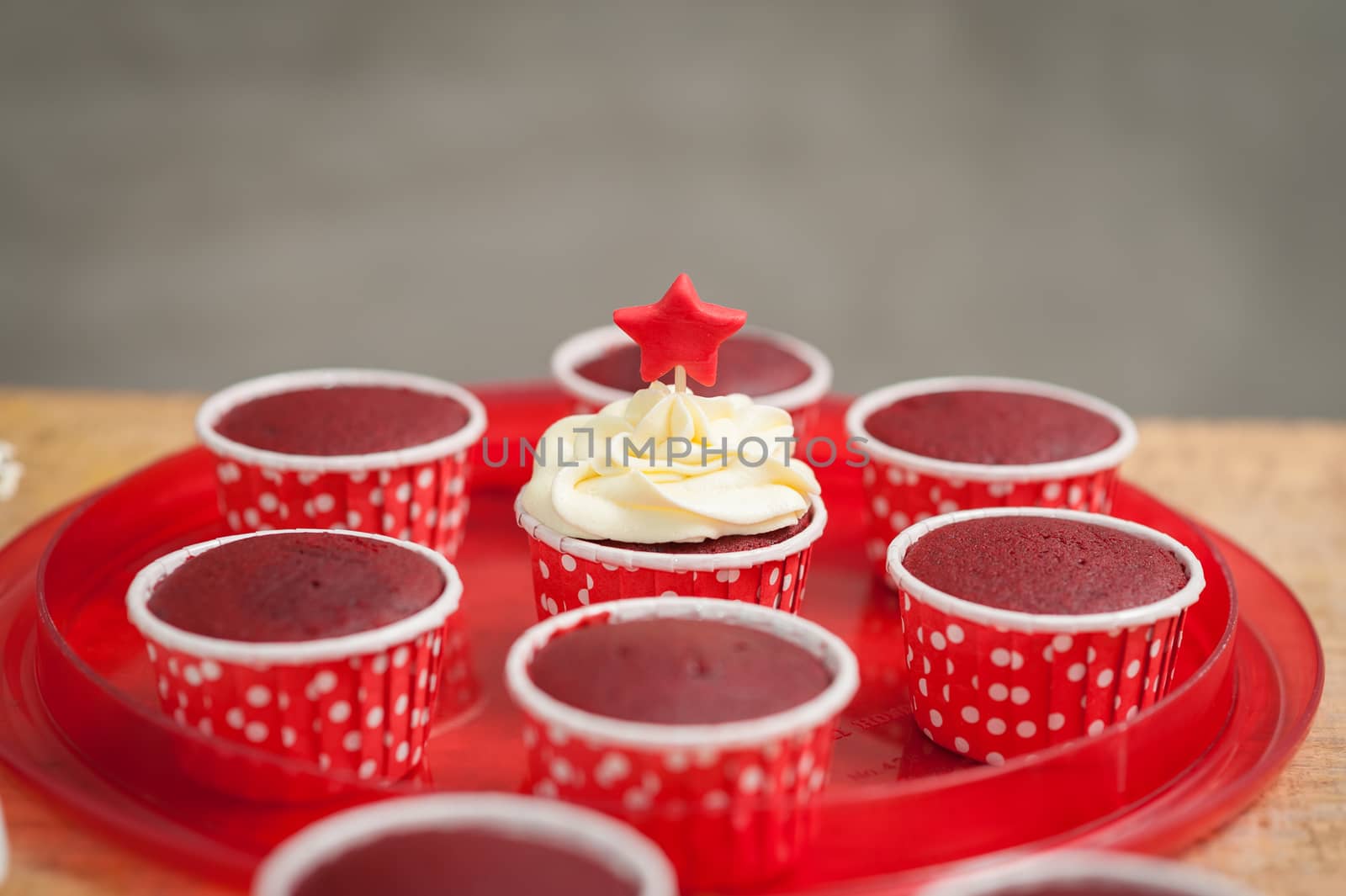 The action of making red velvet cupcakes. one suceed red velvet cupcake with cream cheese and fondant.