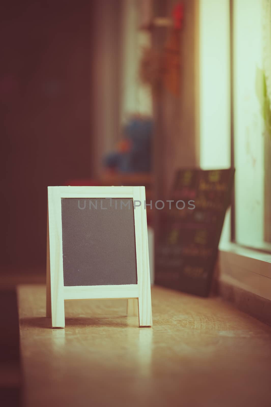 Small A-frame black board with blank area for text or message on wood bar in cafe wih vintage filter effect