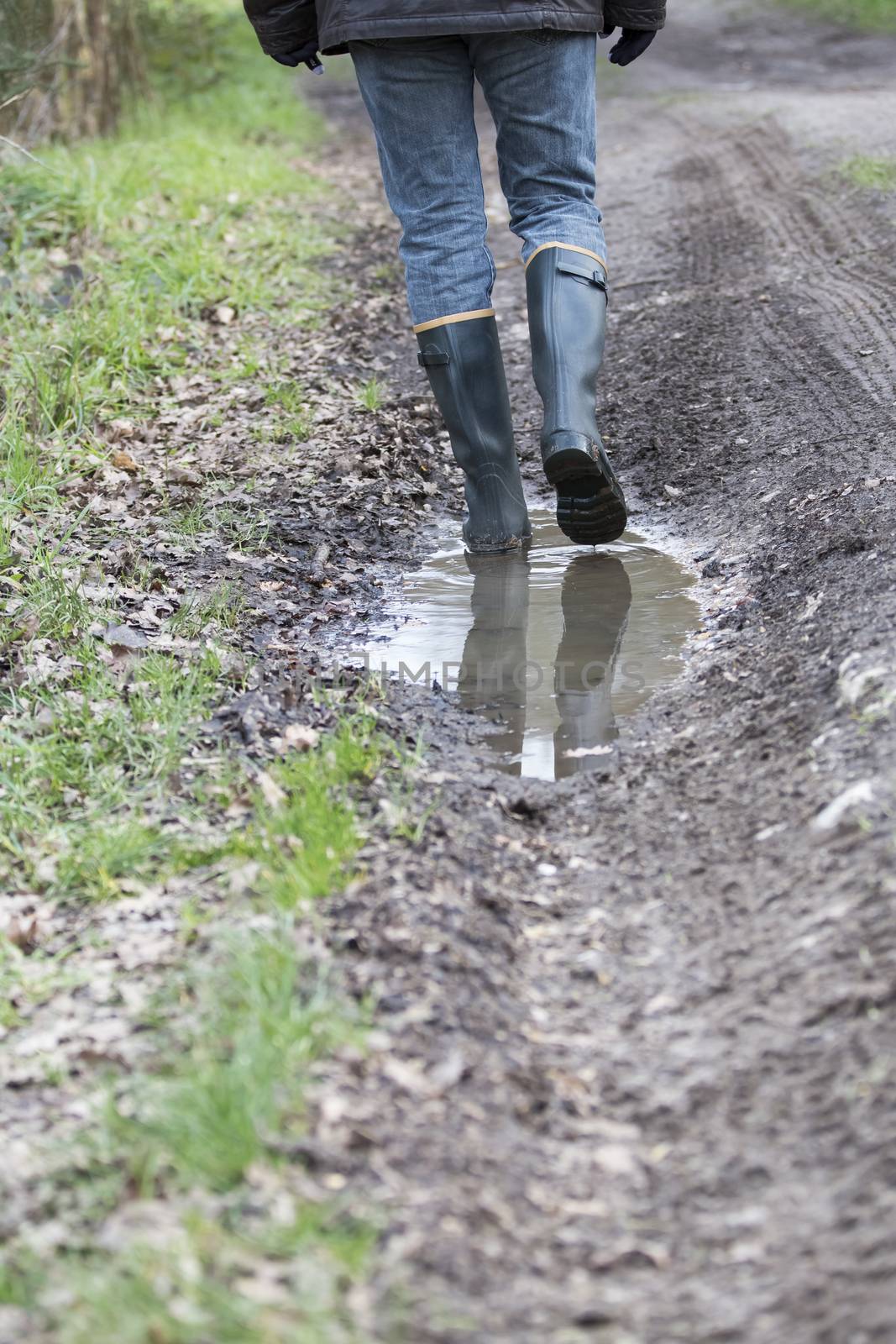 Man with rubber boots walking on rural path