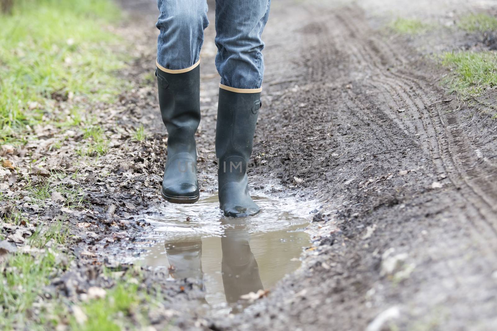 Man with rubber boots walking on rural path