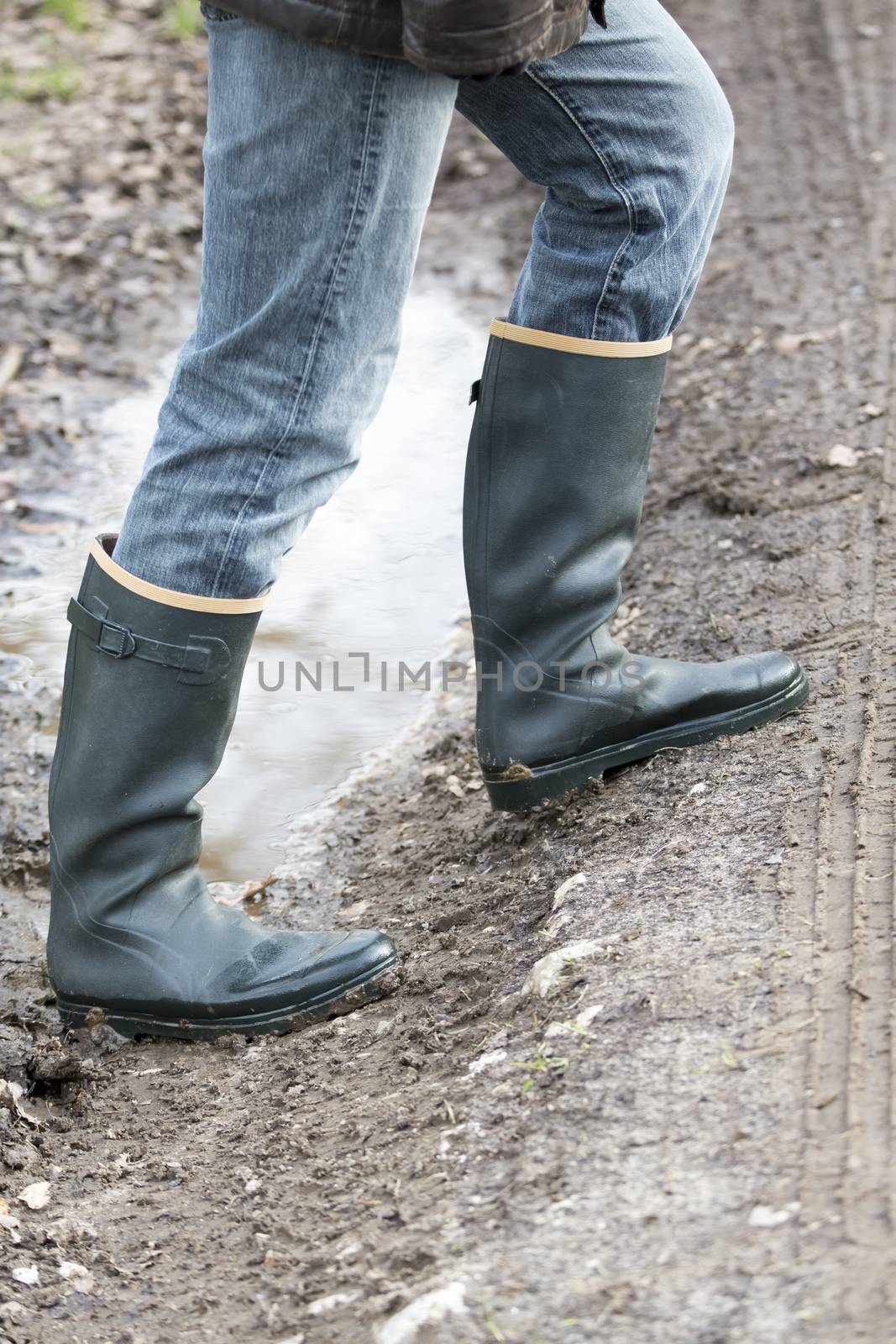 Man with rubber boots walking on rural path