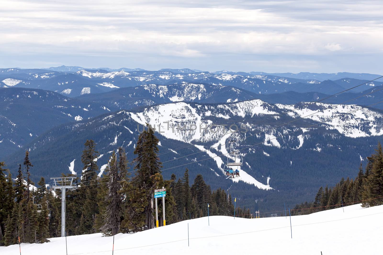 Snowboarders riding Ski Lifts up the slope of Mount Hood Oregon with Cascade Range view in Winter Season