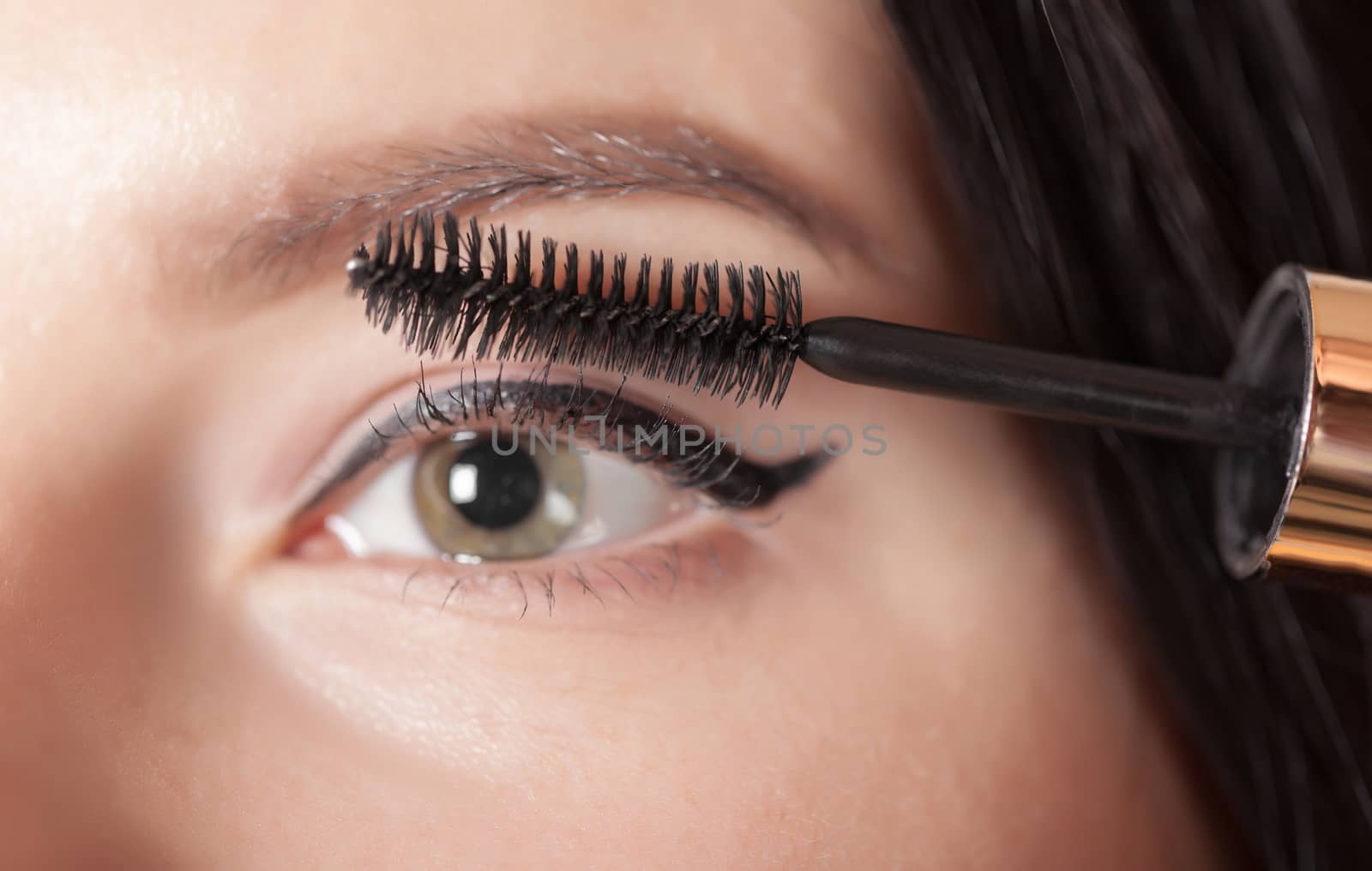 woman paints the eyelashes mascara, eye closeup