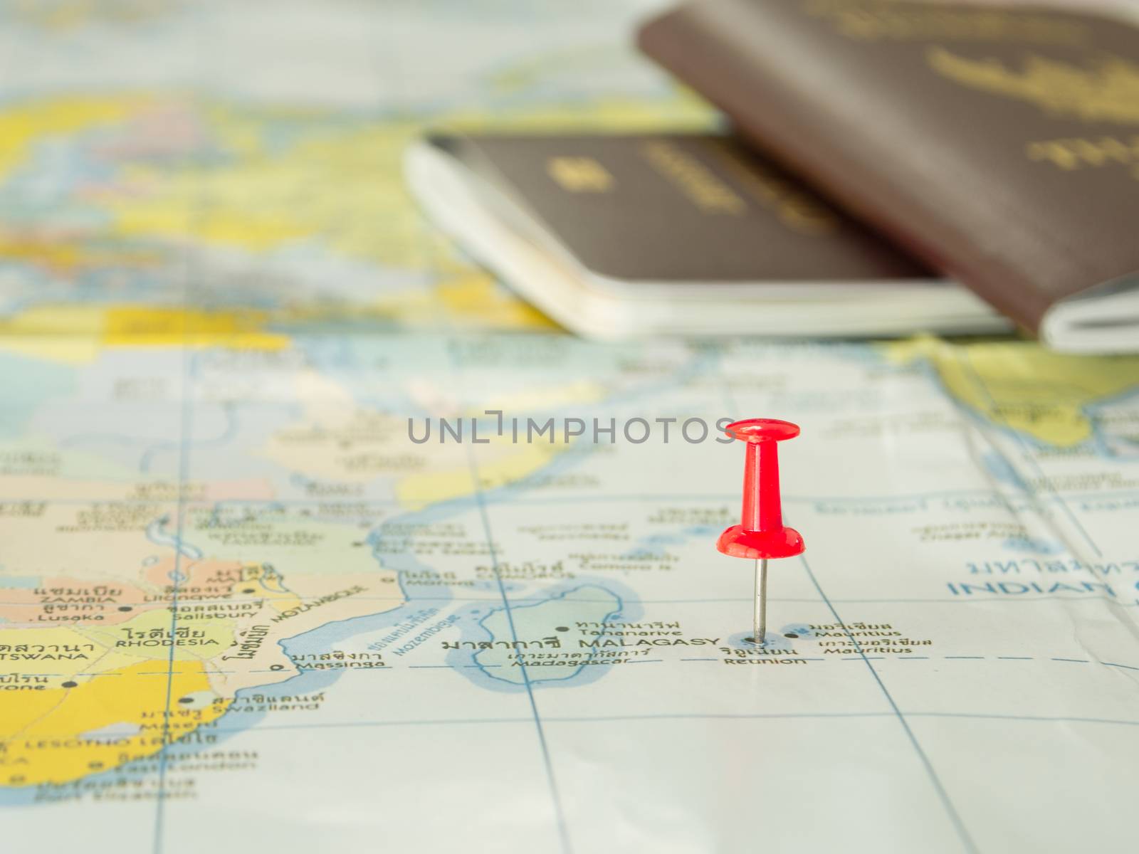 Embroidered red pins on a world map with a passport
