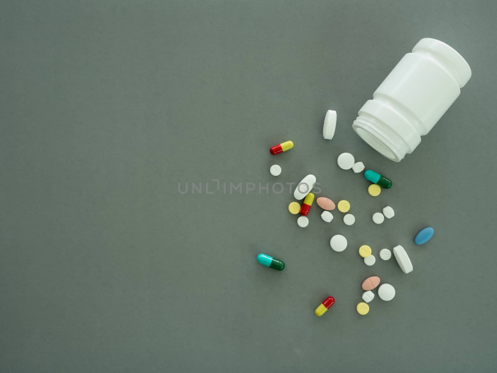 pills and pill bottle on gray background. top view.