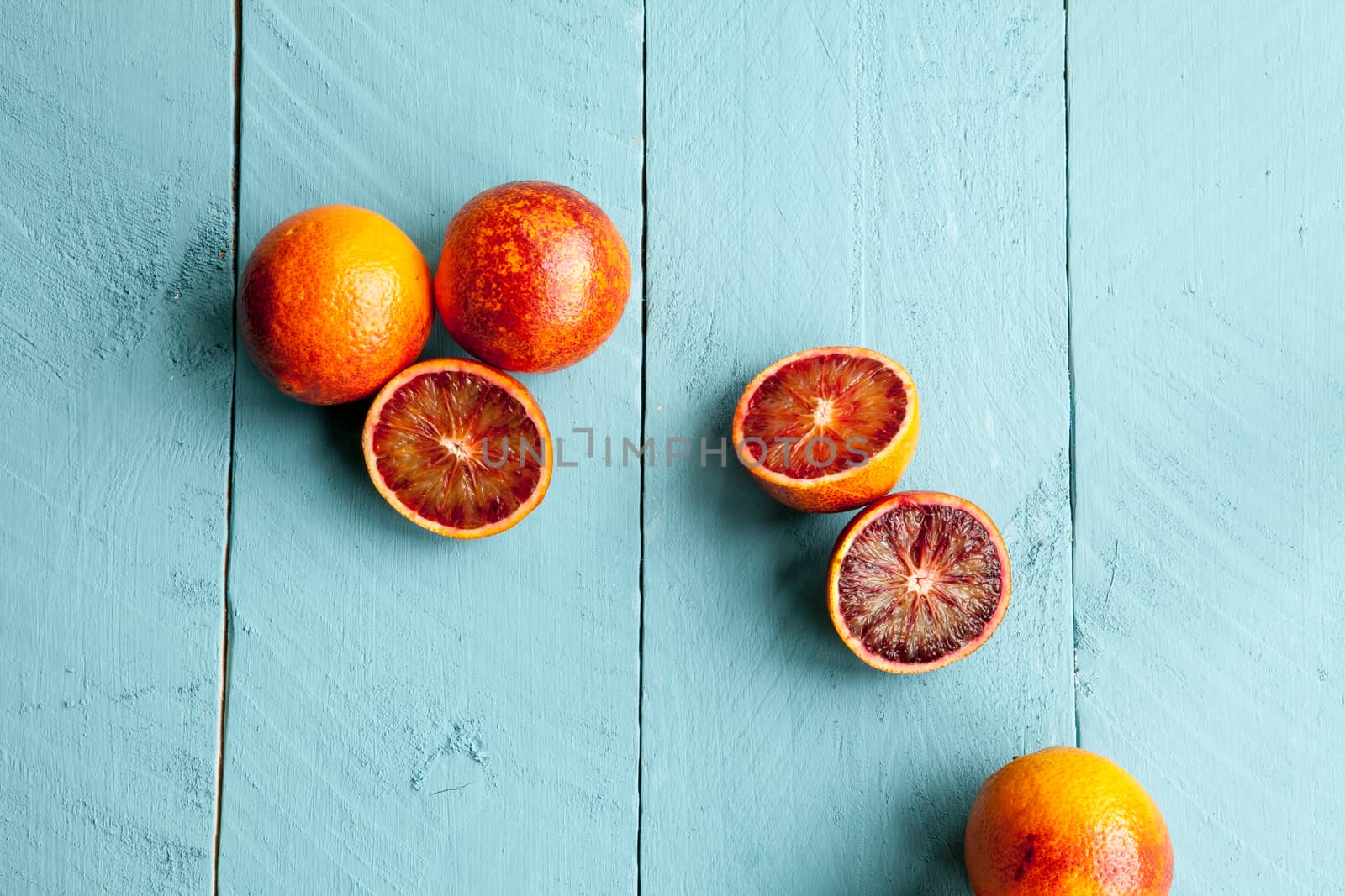 Several sanguine oranges on blue wooden background by andongob