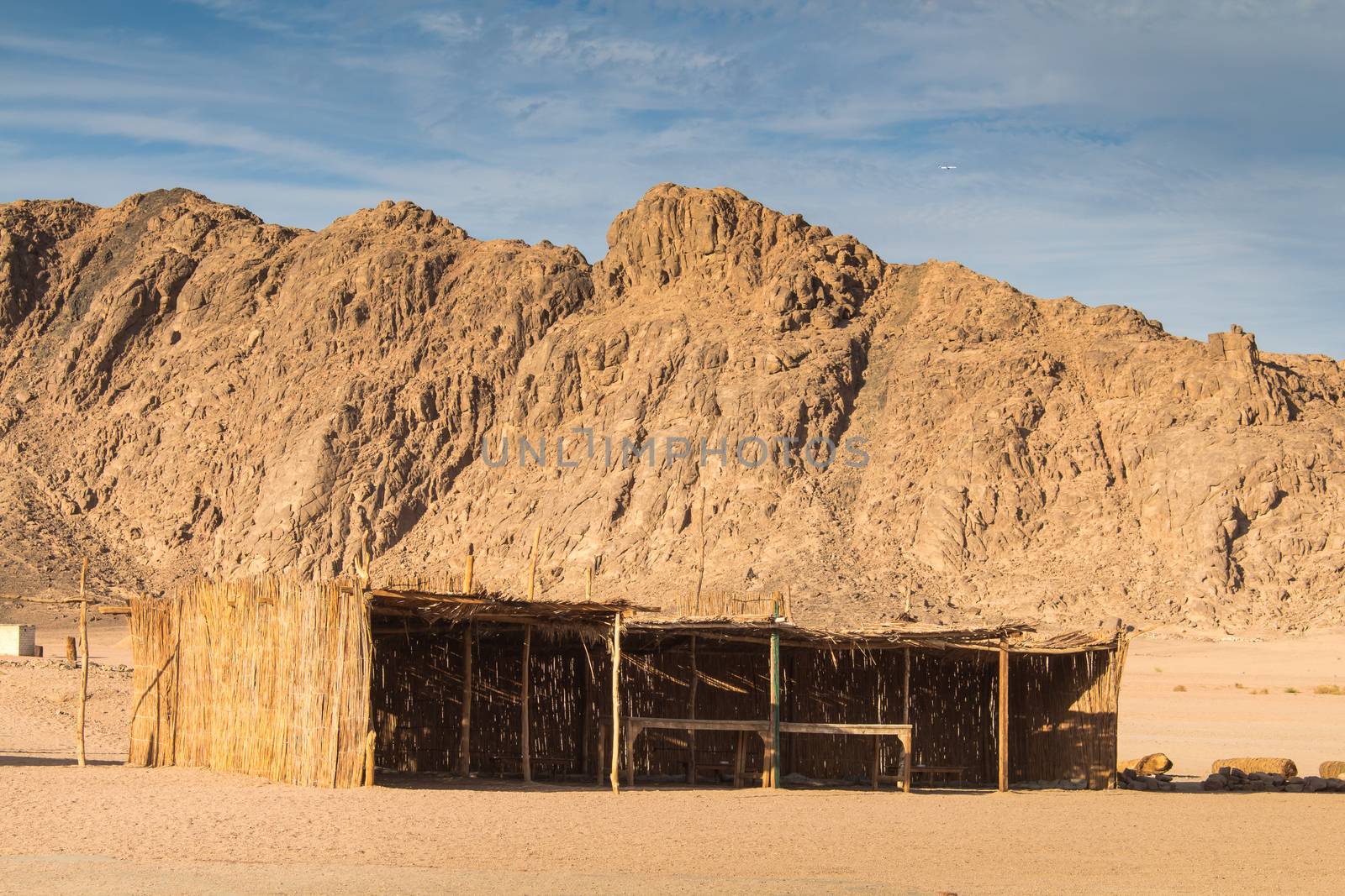 Rocky mountains in the sand color in the desert in Egypt. Bedouin building for the guests. Cloudy sky.