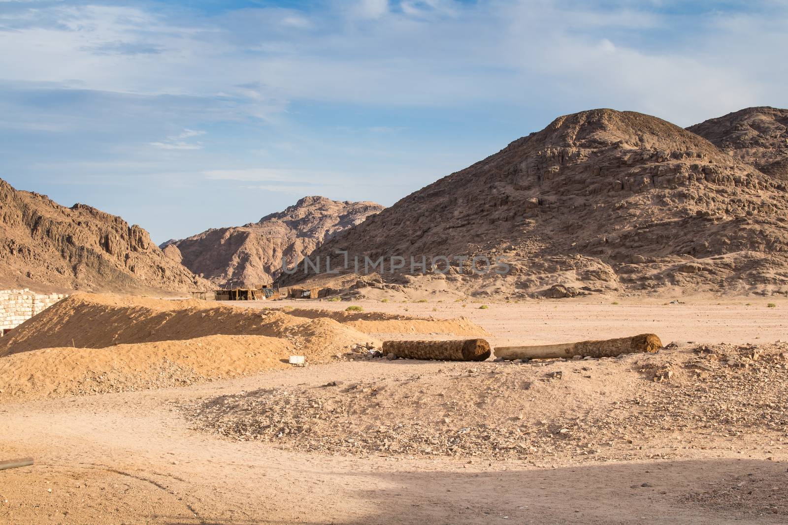 Rocky hills in the desert in Egypt, surrounding a bedouin village. Cloudy sky.