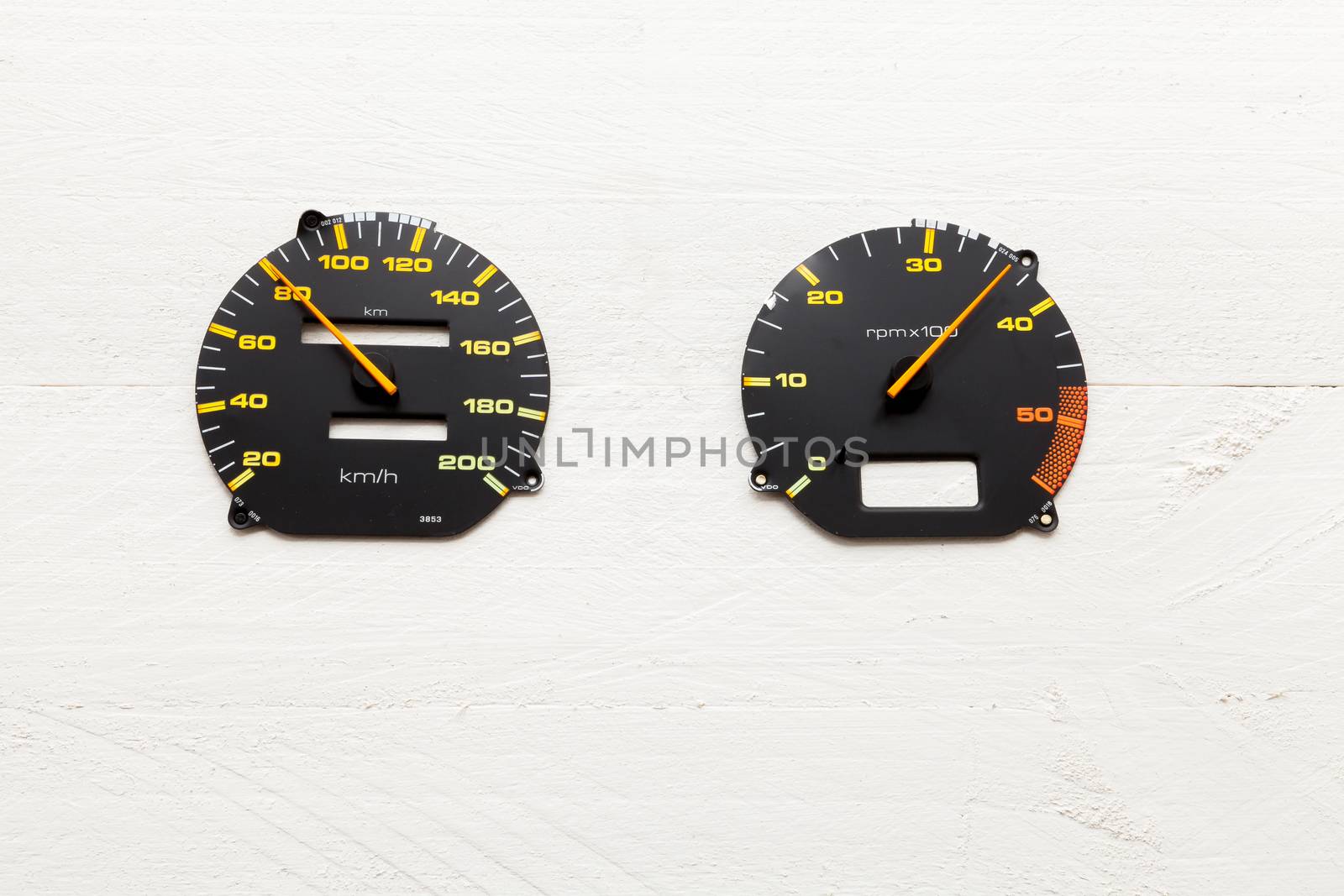 Car speedometers on white wooden background view from above